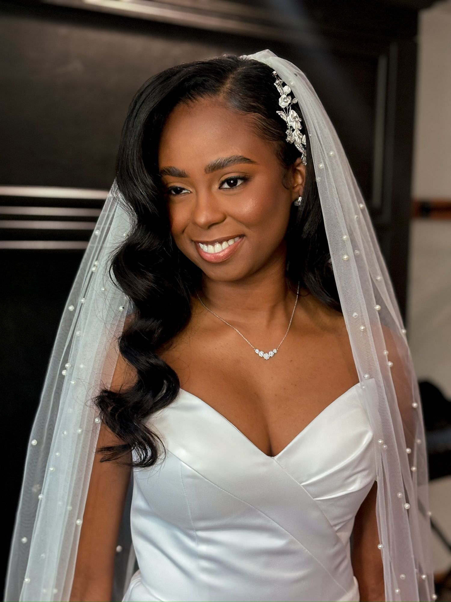 Elegant bride wearing a classic white wedding gown and veil poses indoors.