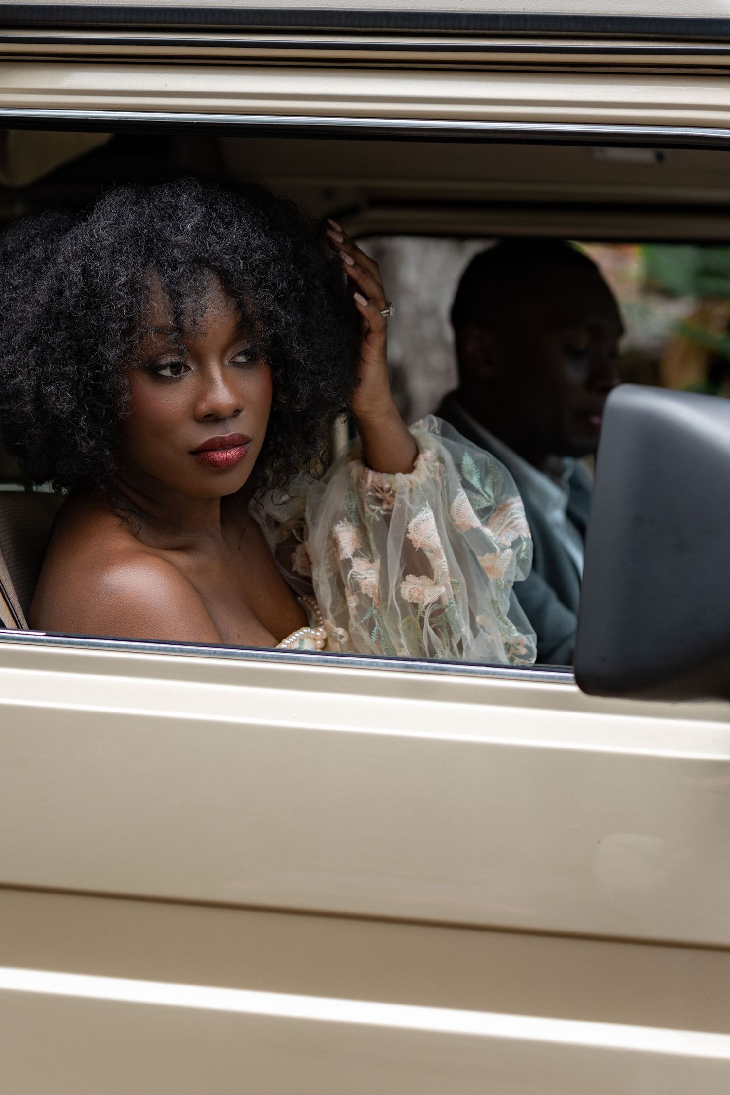 Artistic bridal portraits taken through the window of a vintage cream-colored car.