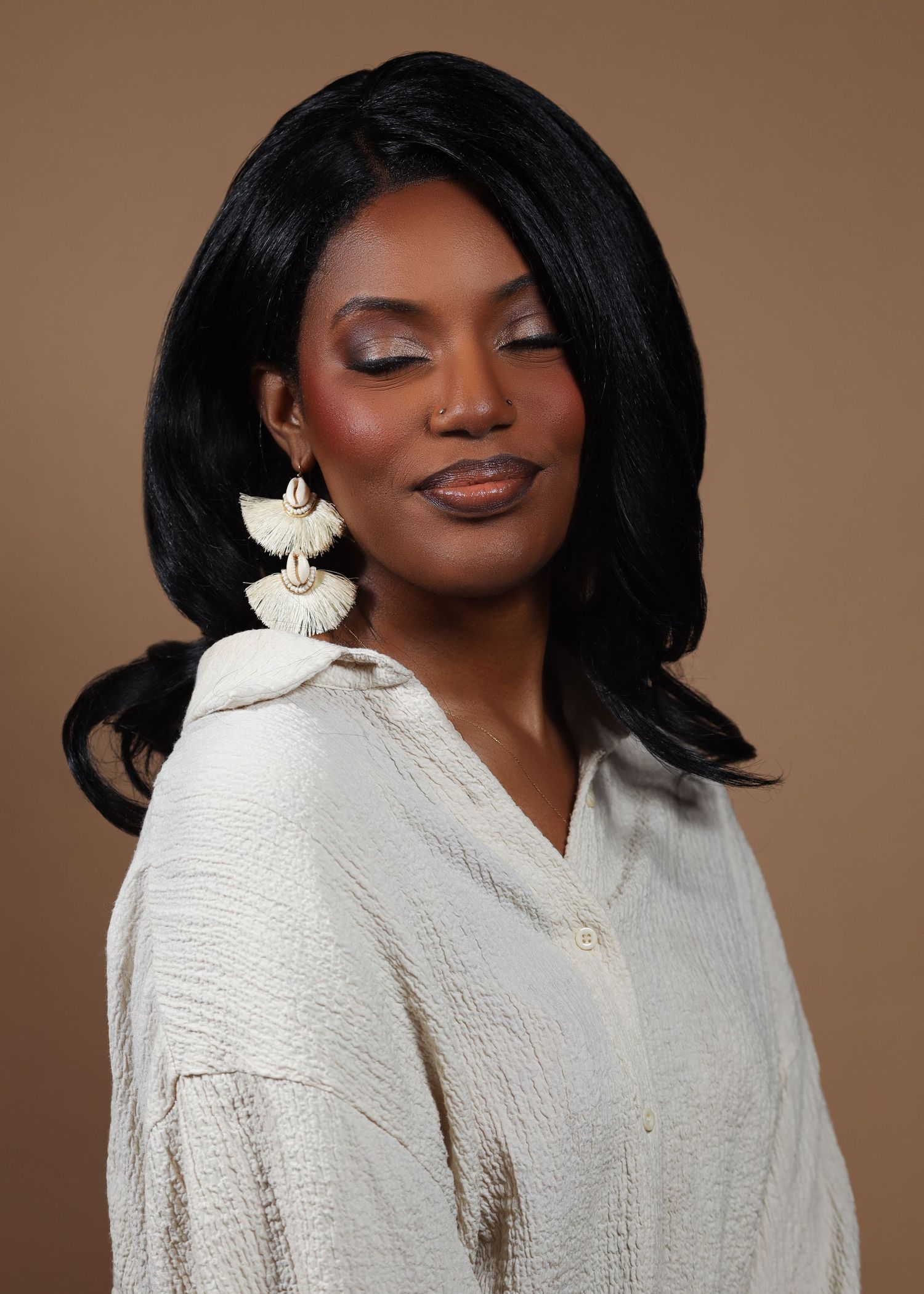 Professional portrait featuring textured white clothing against warm brown backdrop.