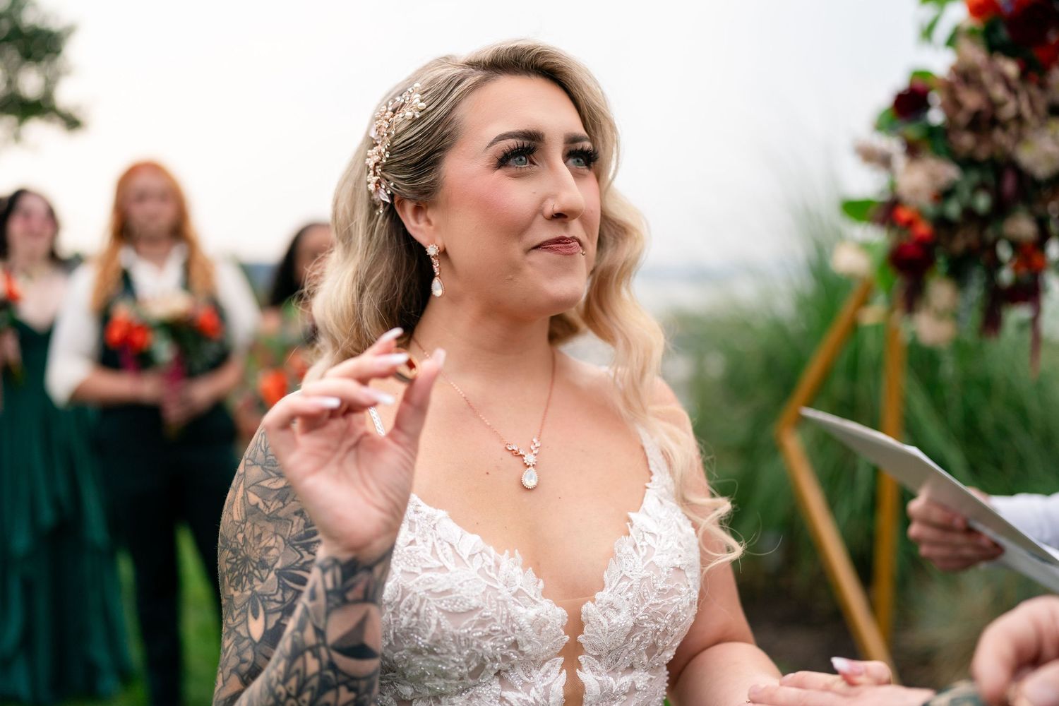 Joyful bride in lace wedding dress sharing laughs with wedding party outdoors.