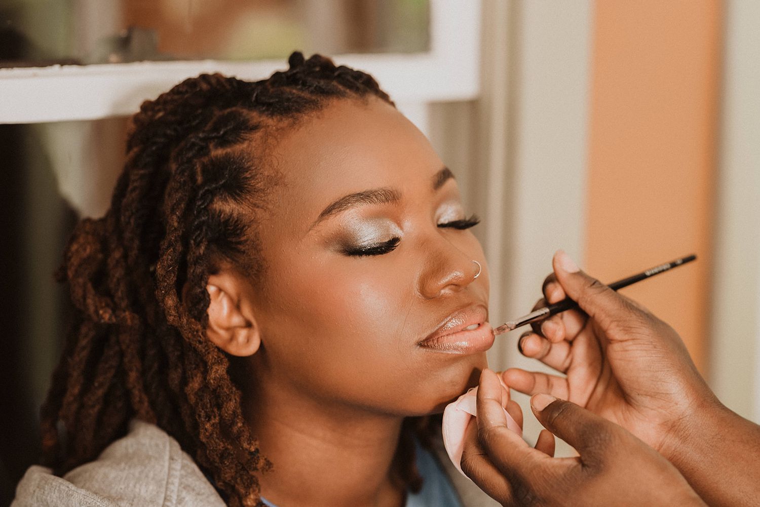 Professional makeup artist applying cosmetics during wedding preparation.