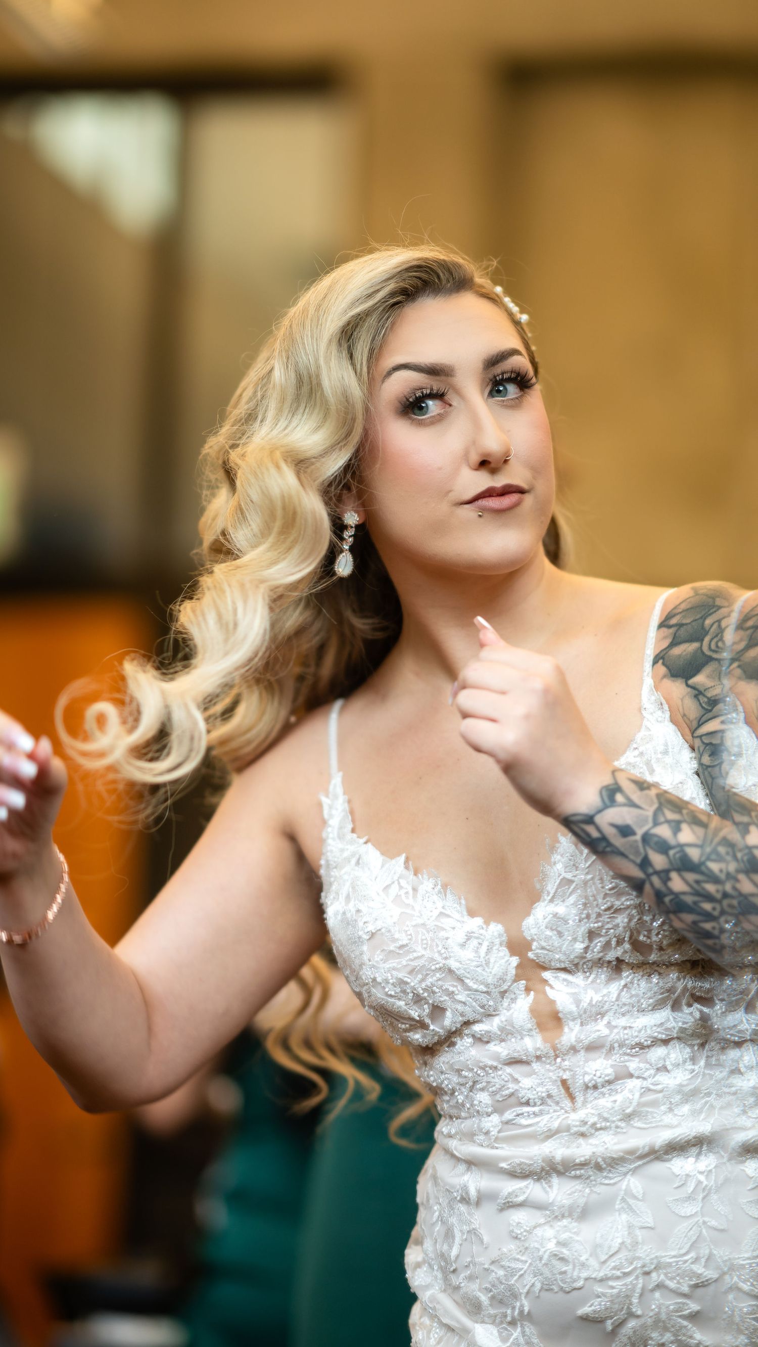 An elegant bride with wavy blonde hair wearing a detailed lace wedding gown.