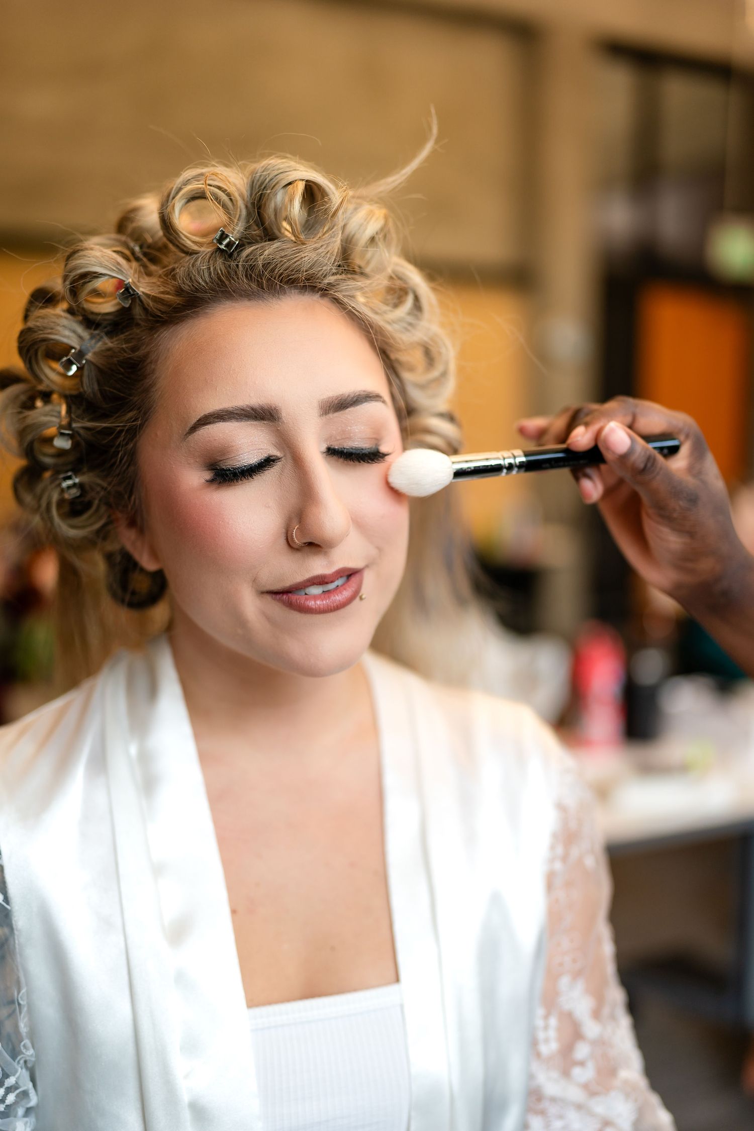 Makeup artist applying finishing touches to bride's wedding day look.