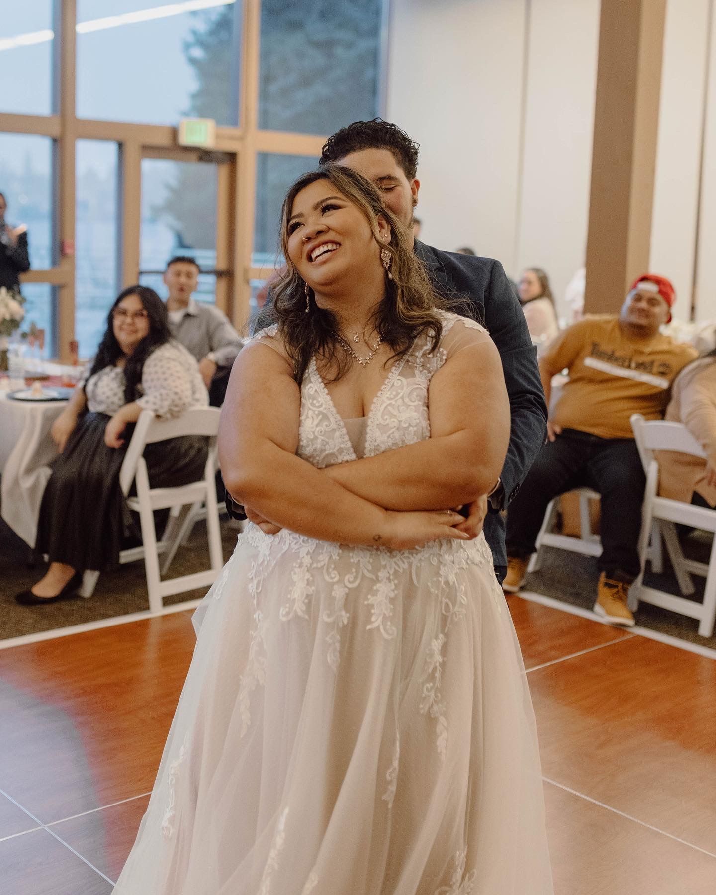 Wedding celebration in an indoor venue with white decor and natural lighting.