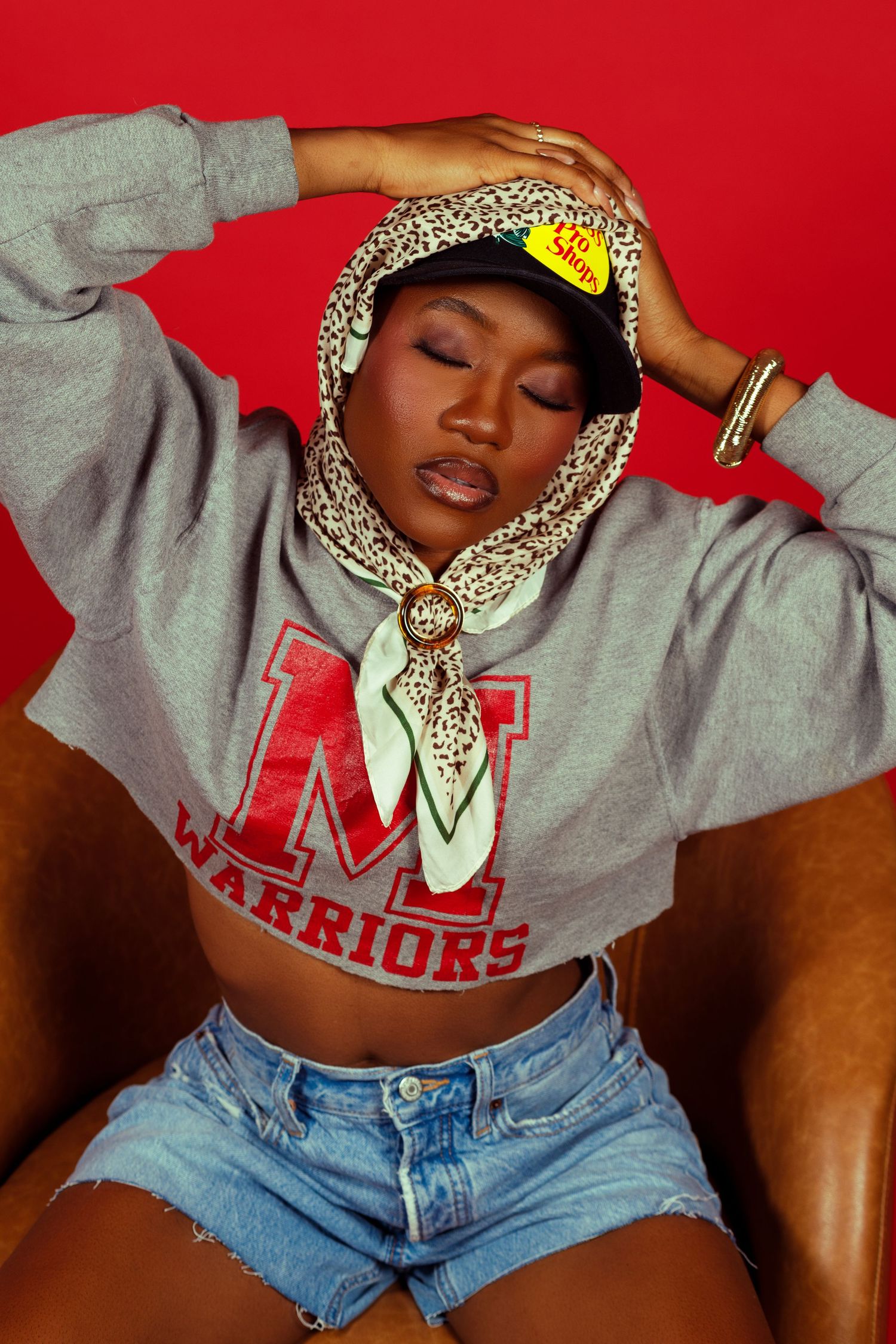 Casual fashion shots in grey hoodie and denim shorts against red background.