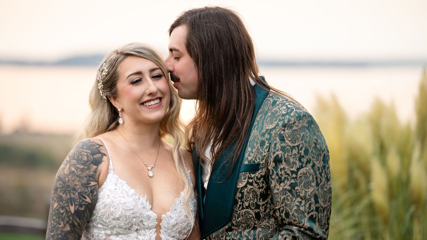 A tender moment between newlyweds at sunset with natural scenery in the background.