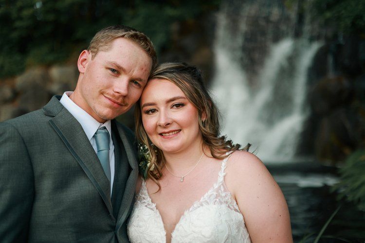 A romantic moment captured against a misty waterfall backdrop.
