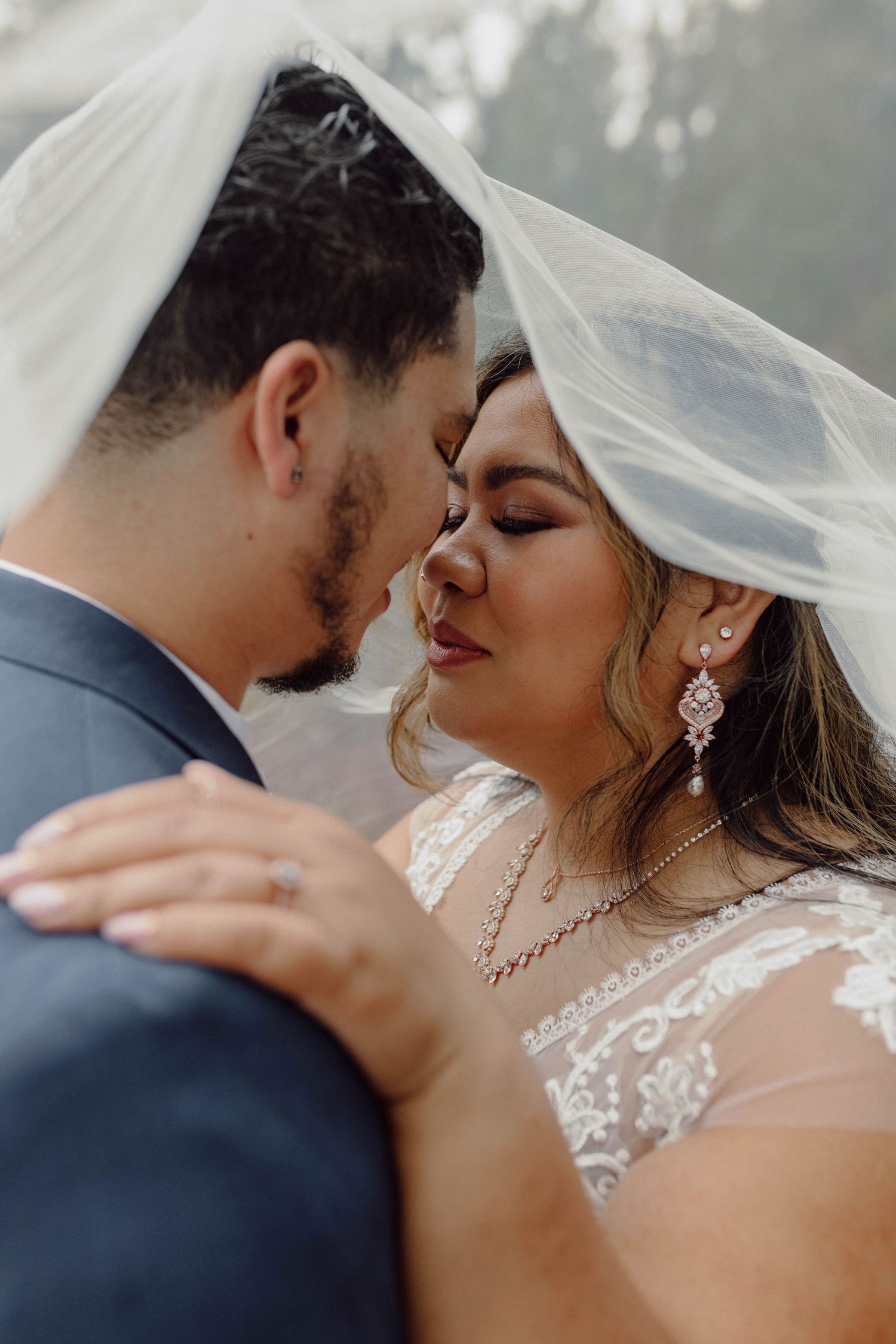 Close-up romantic wedding photos showing tender moments between newlyweds with delicate veil and elegant jewelry details.
