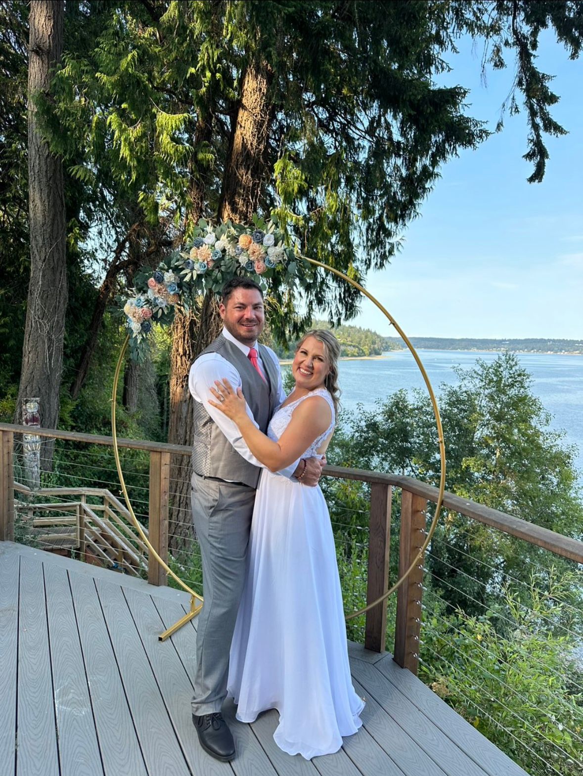 A couple shares a tender moment on a wooden deck overlooking a serene waterfront.