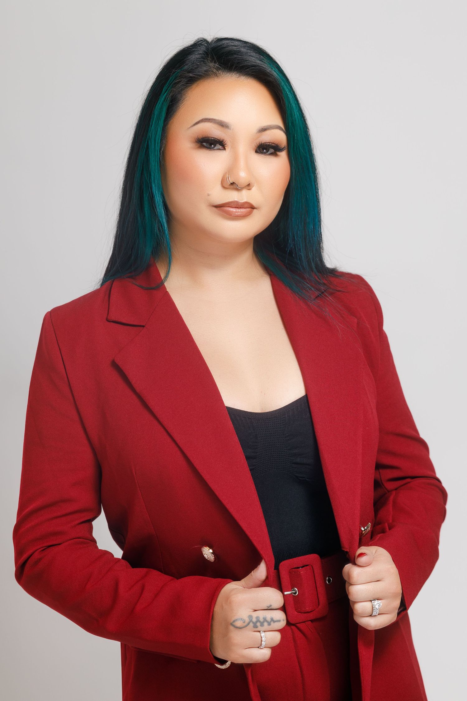 Professional fashion photo series showing a red blazer styled with a black top and teal-colored hair against grey background.