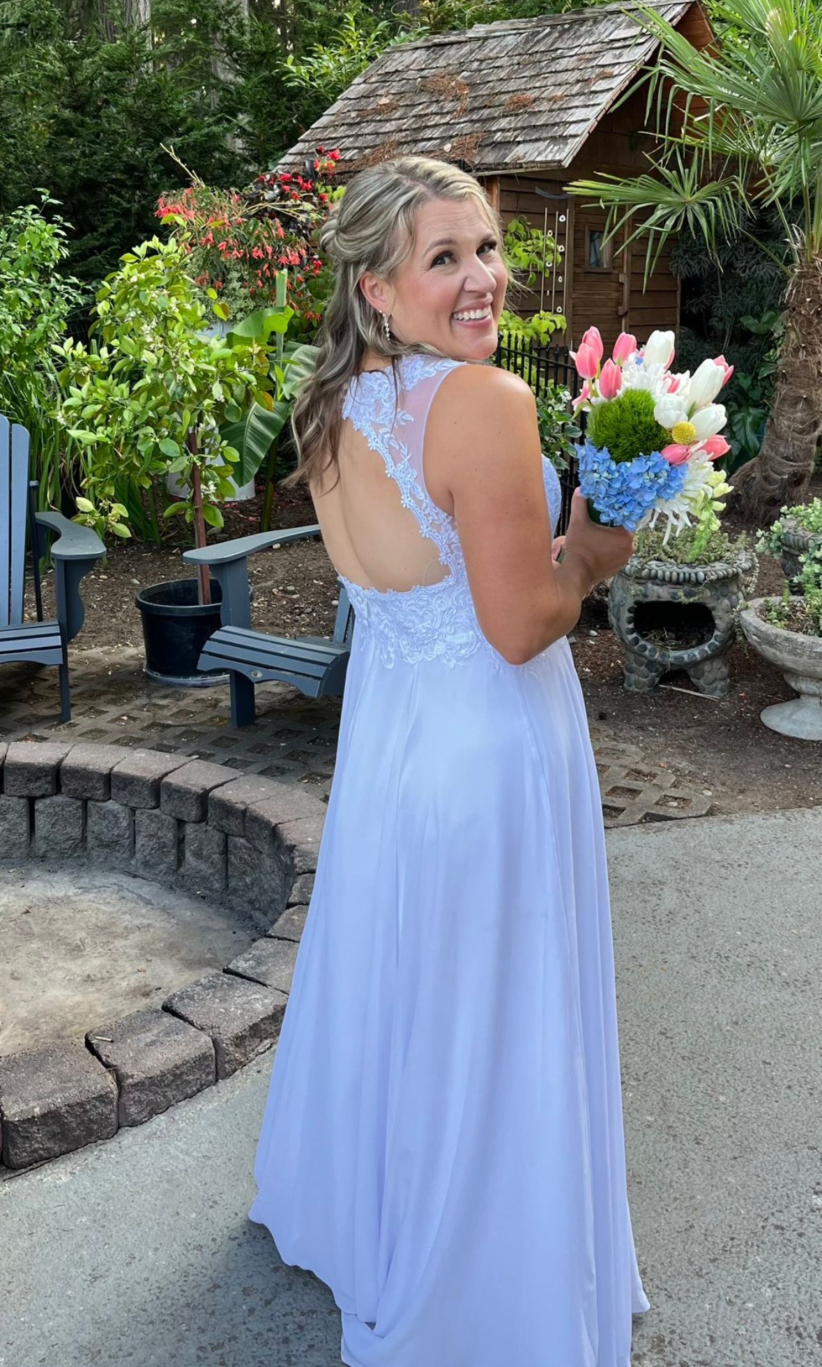 A bride in a flowing white dress twirls joyfully in a garden setting.