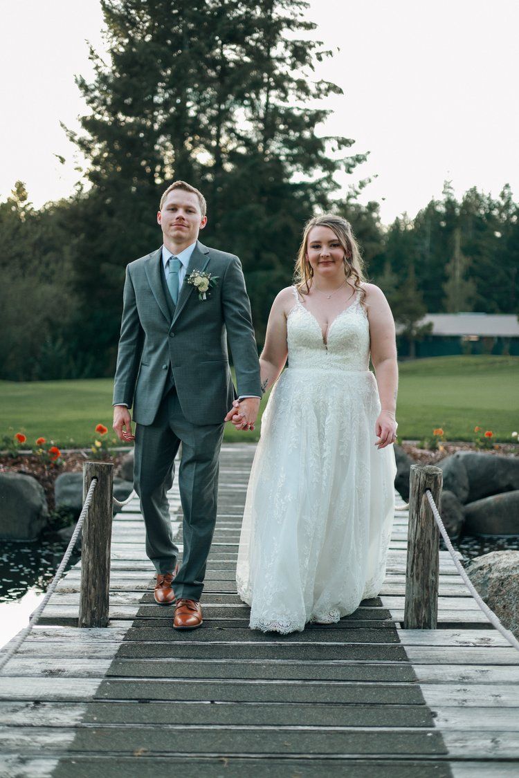 A couple walks hand in hand along a rustic wooden dock.