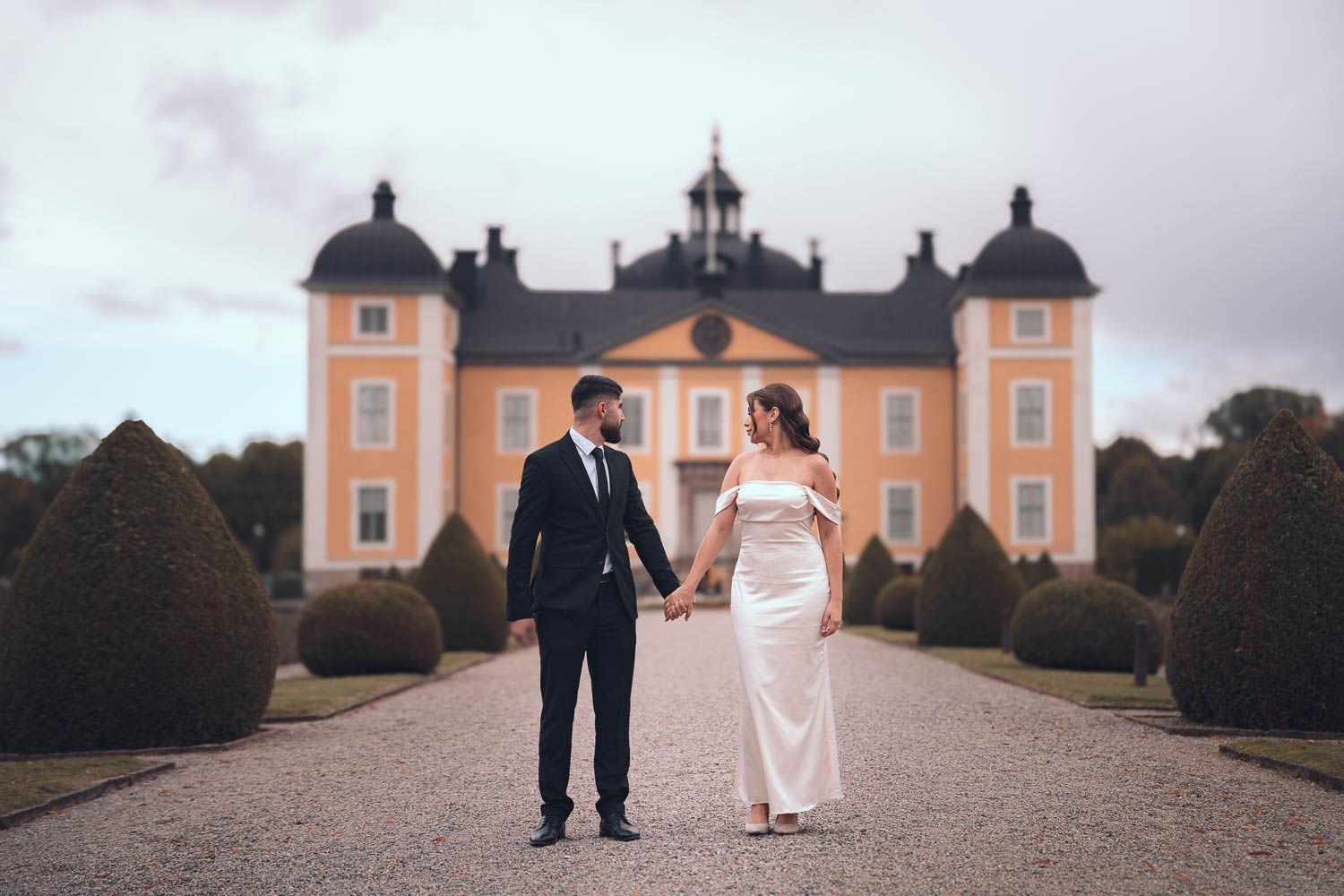 Ny förlovade brudpar håller hand står och tittar mot Strömsholms slott utanför Västerås