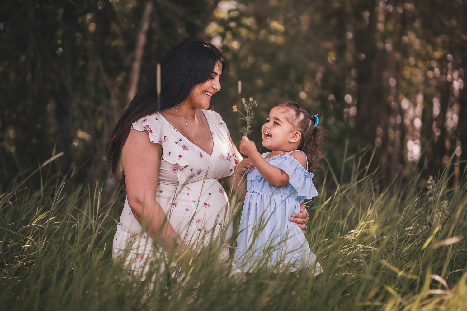 En gravid kvinna med en somrig outfit fotograferas med hennes dotter en sommar dag i Eskilstuna