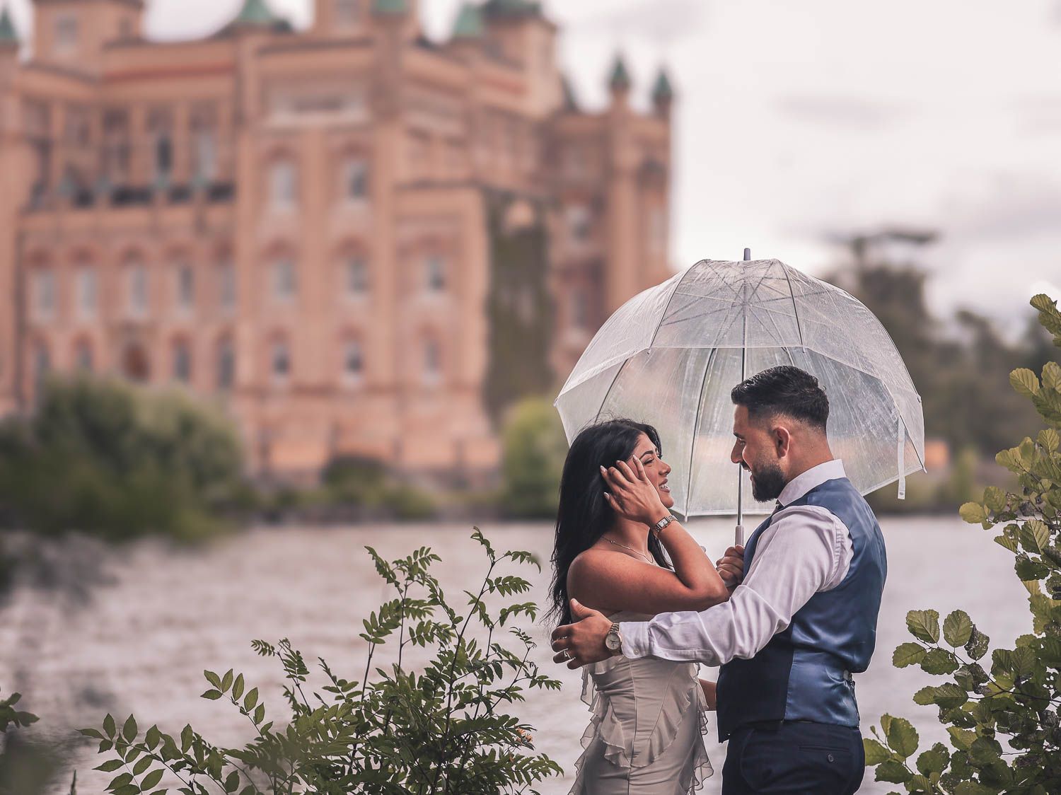 par håller en genomskinlig paraply en regnig dag utanför ett slott