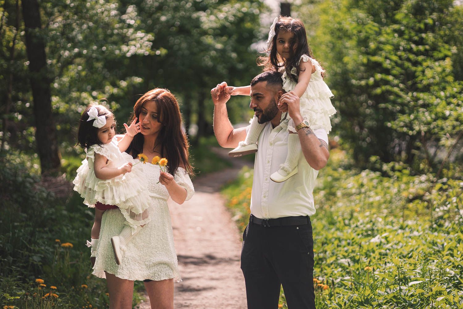 Familj i ljusa sommarkläder promenerar i skogen under en varm sommareftermiddag.