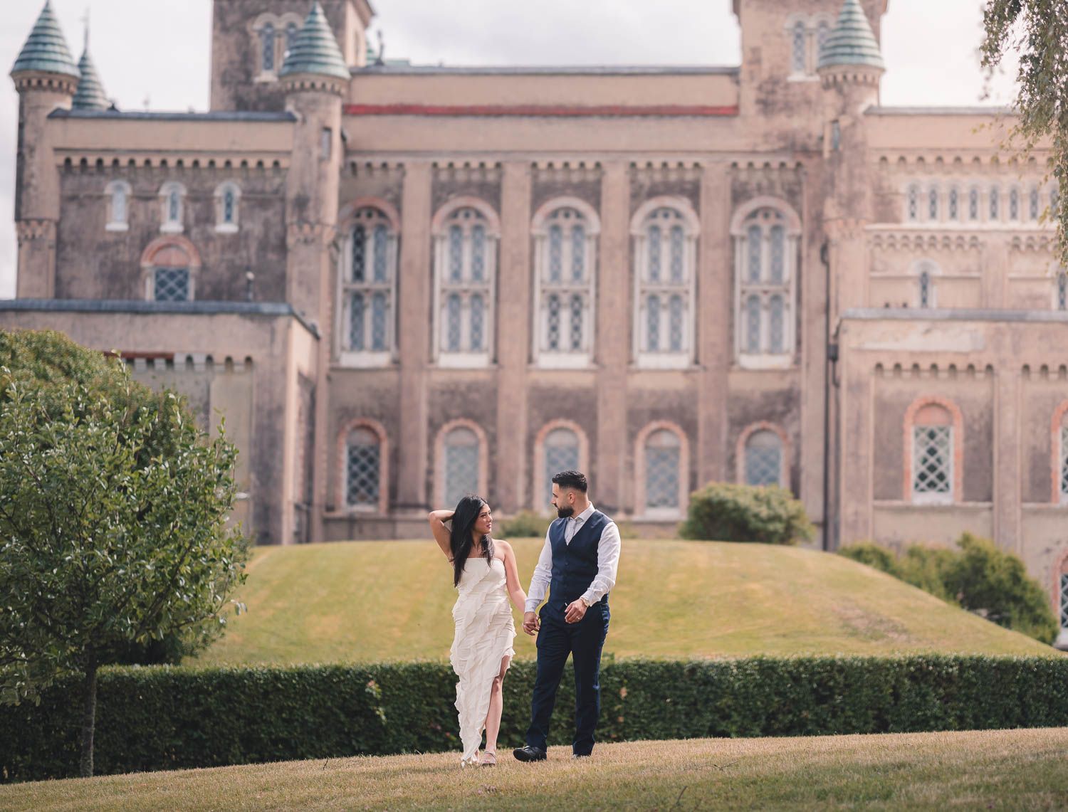 par går hand i hand och tittar på varandra utanför ett slott i eskilstuna