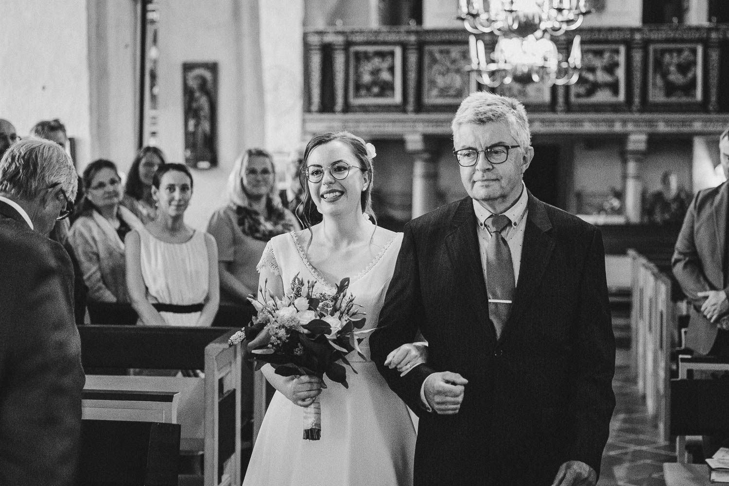 Bröllopsbrud håller i sin pappas arm och går tillsammans in i kyrkan för att möta brudgum