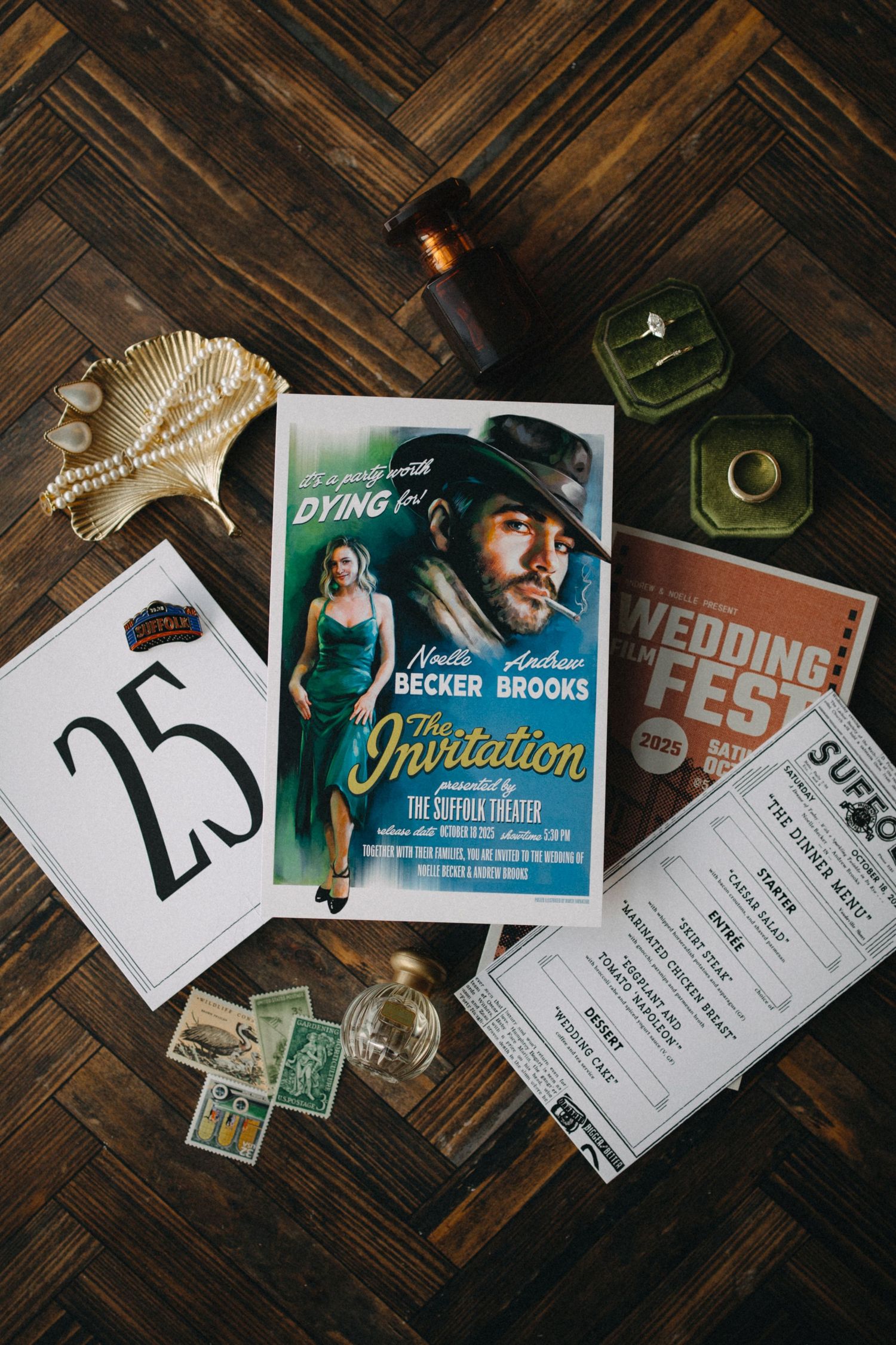 Vintage movie poster wedding stationery flat lay with table number 25, stamps, rings, and wedding details on wood floor.
