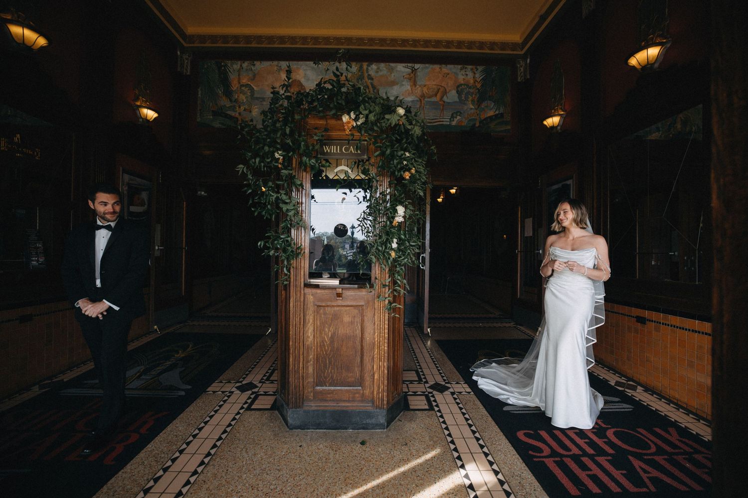 Bride and groom share a first look moment in an elegant hotel lobby adorned with lush greenery.