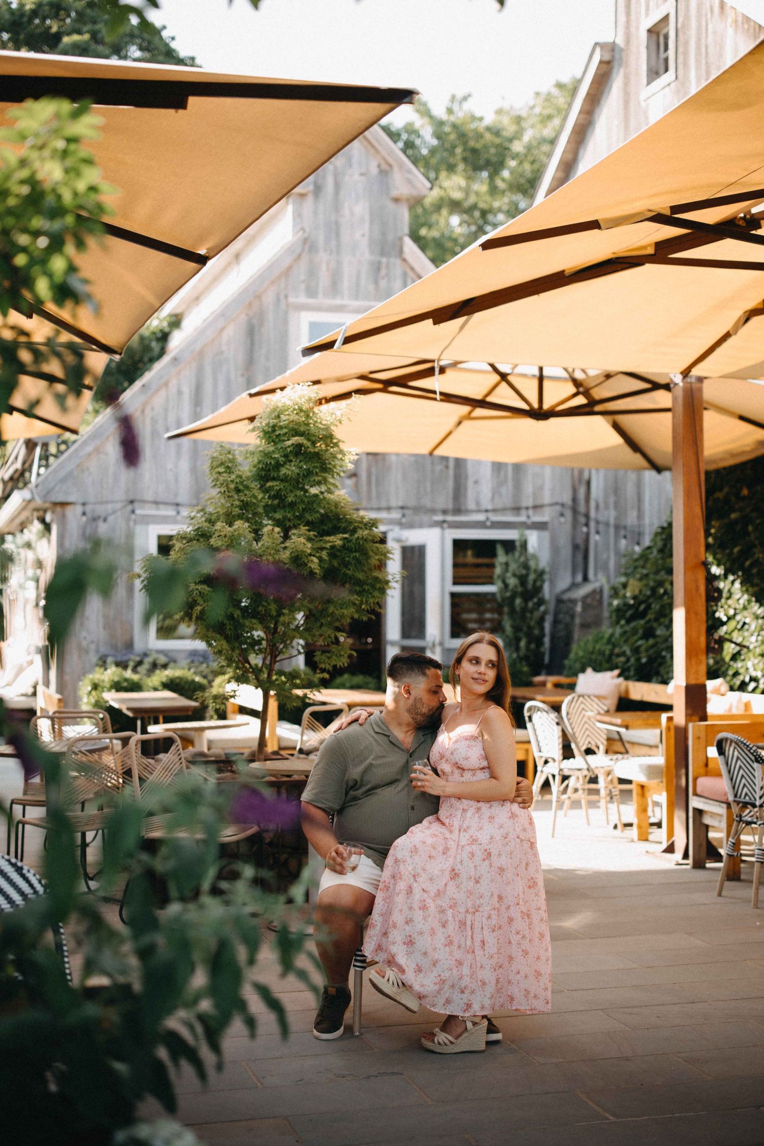 Couple sitting together under yellow patio umbrellas at a rustic outdoor restaurant venue.