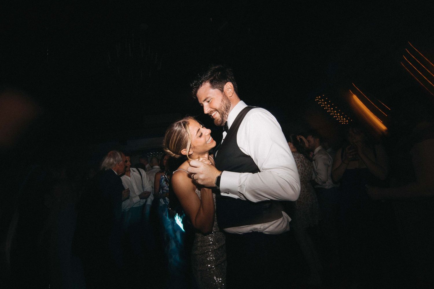Bride and groom sharing intimate first dance at romantic dark wedding reception.