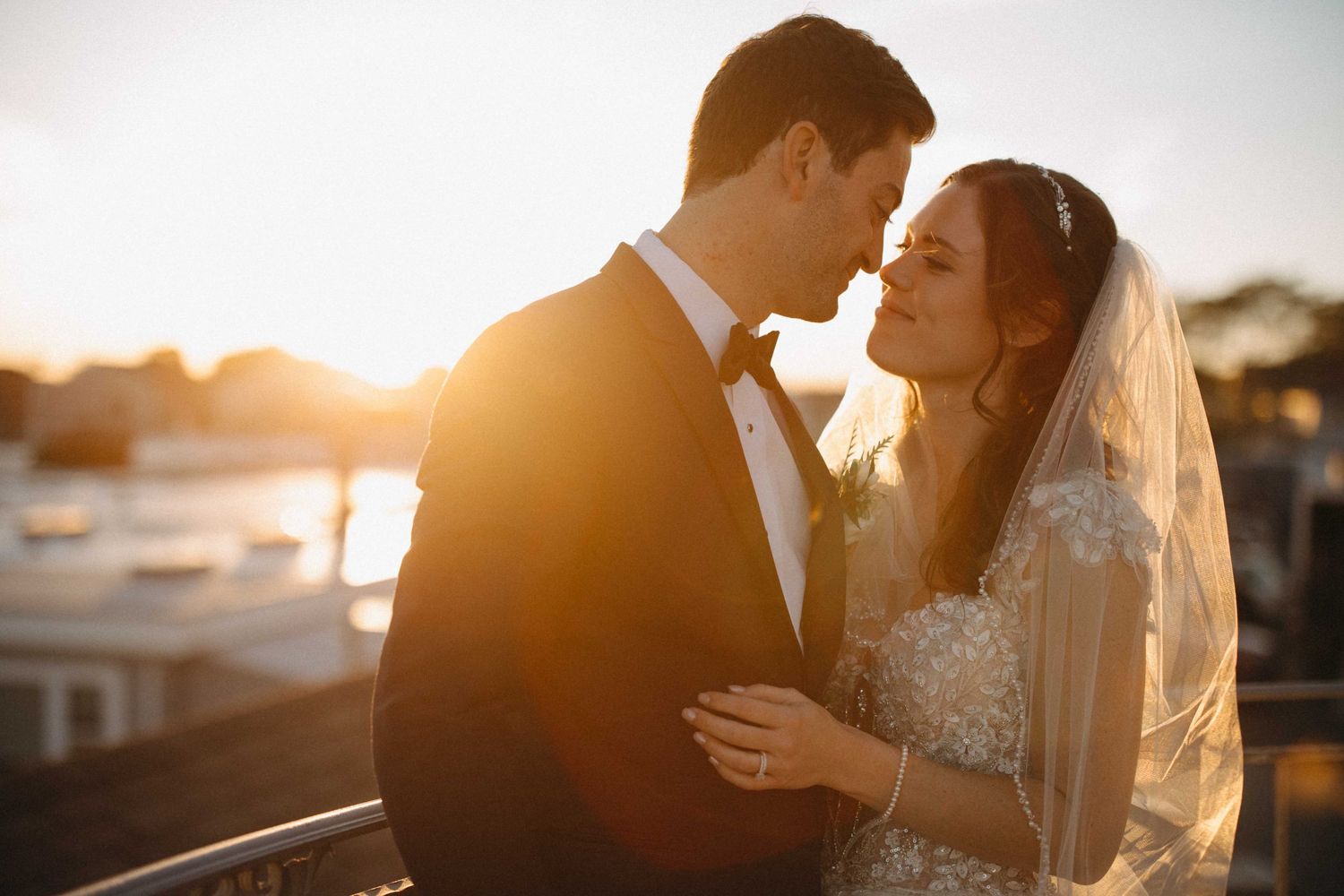 Bride and groom share romantic golden hour moment on rooftop balcony at sunset.