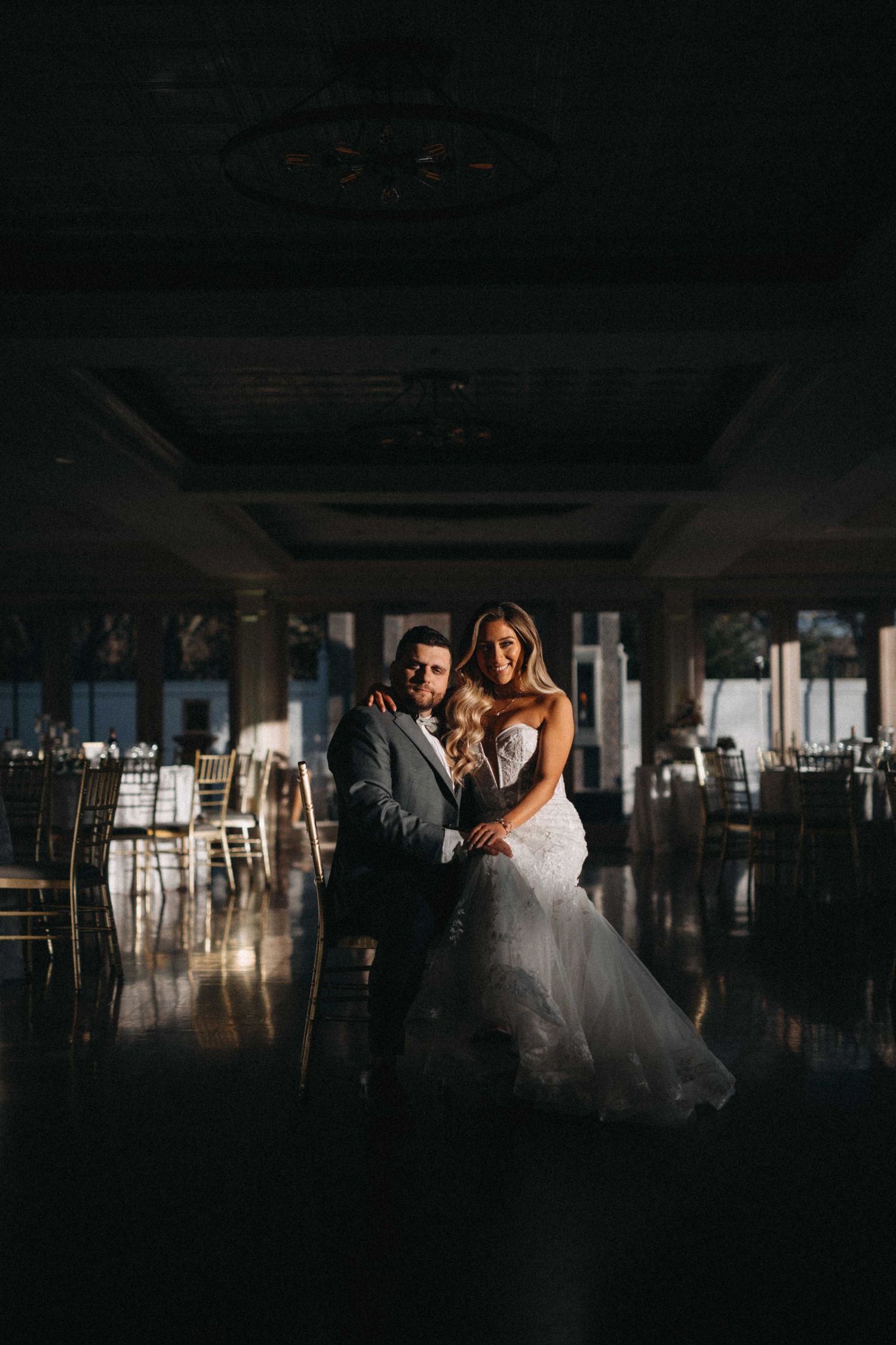 Bride and groom share a romantic embrace on a reflective dance floor in a grand ballroom.