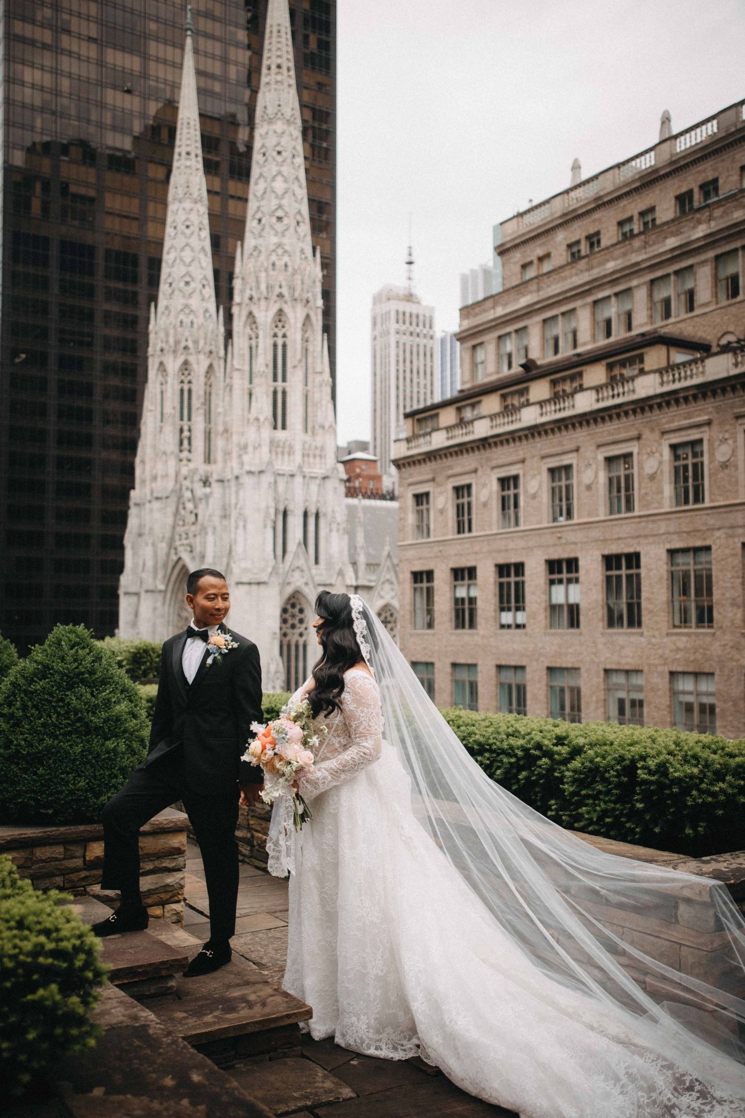 Bride and groom portrait on rooftop terrace with St. Patrick's Cathedral spires in New York City.