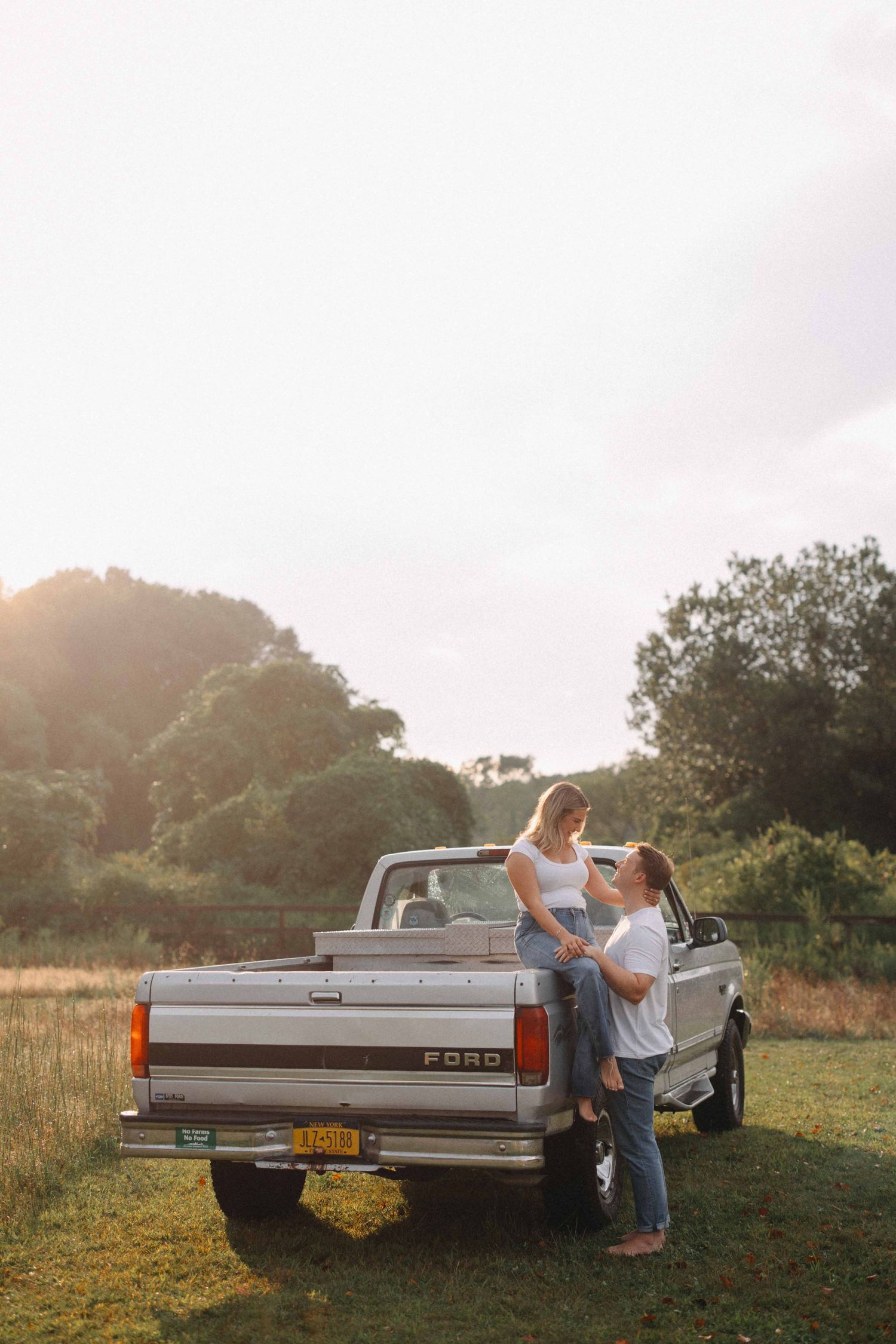 Couple sharing a tender moment beside a vintage Ford pickup truck at sunset.