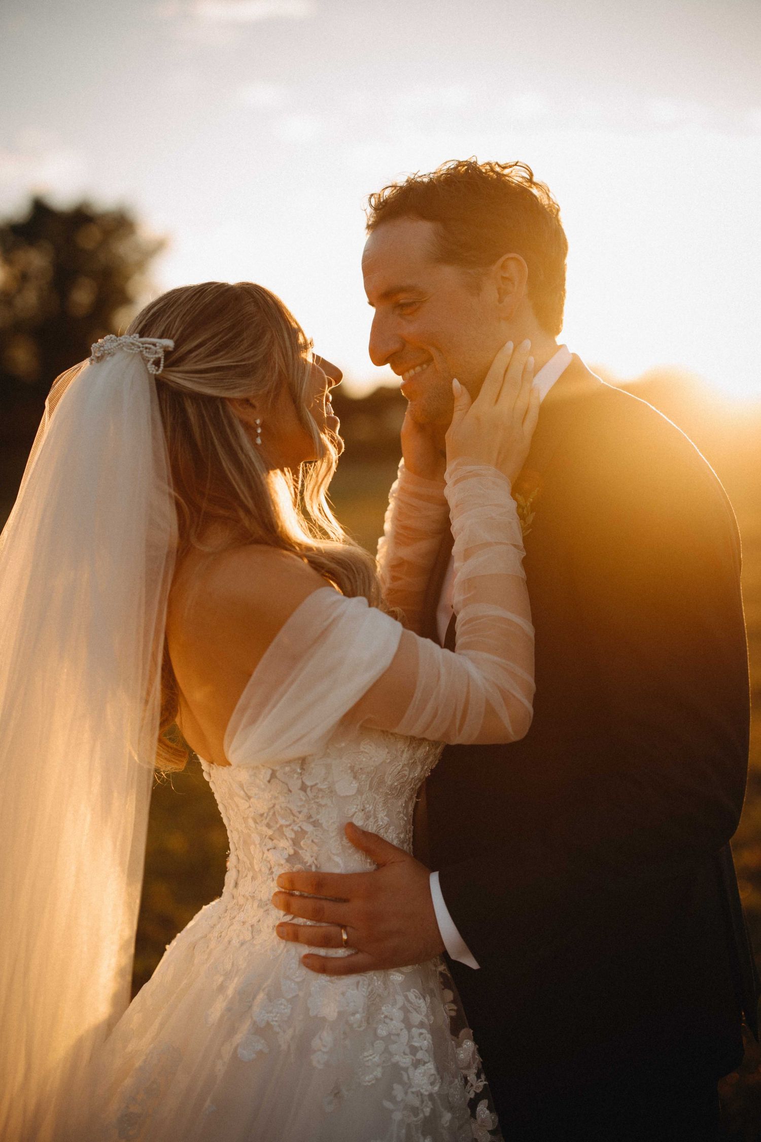 Bride and groom laughing together in warm golden sunset light during outdoor wedding portraits.