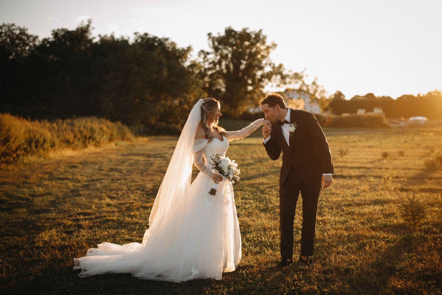 Bride and groom sharing a romantic golden hour moment in an open field at sunset.