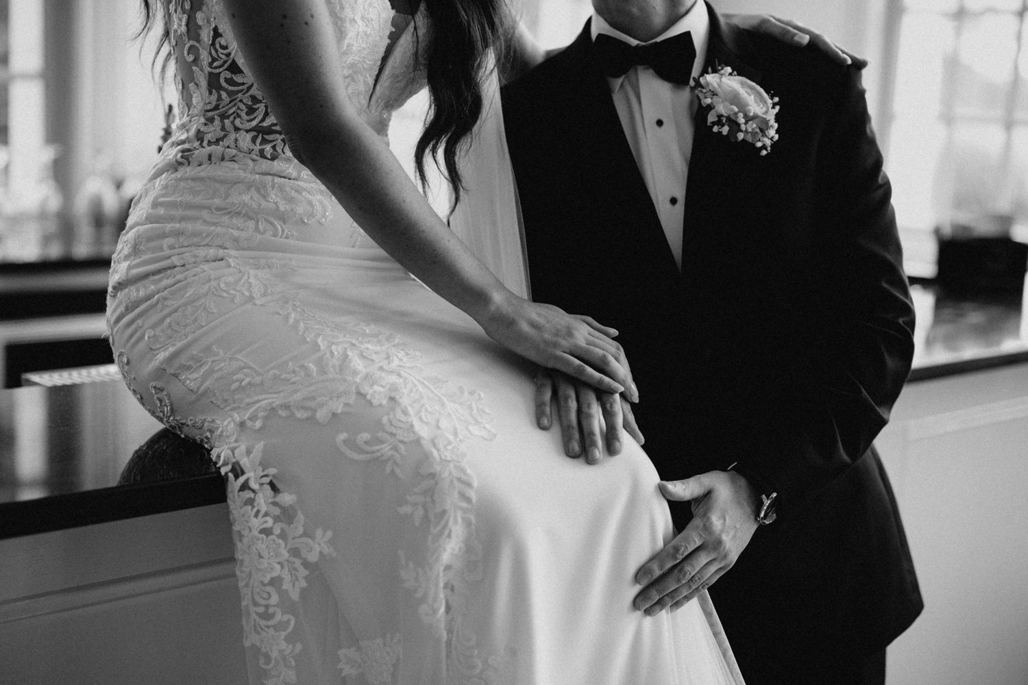 Black and white close-up of bride and groom sharing an intimate moment at the bar.