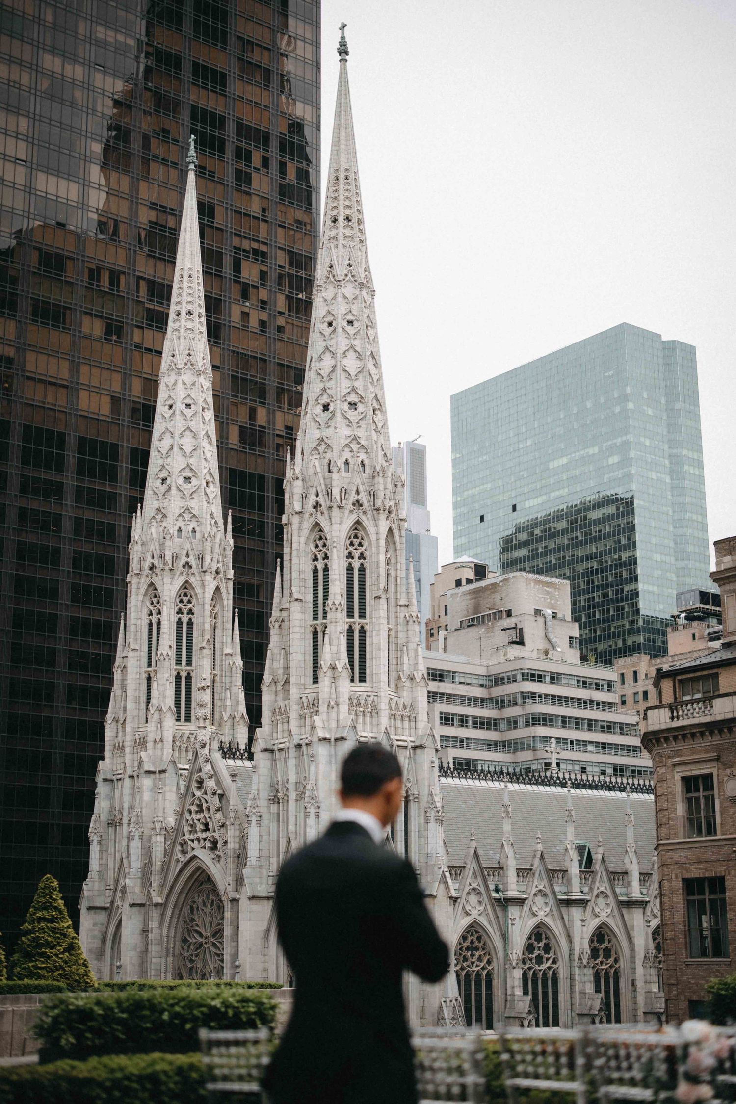 Groom in a black suit standing in front of Saint Patricks Cathedral in New York City.
