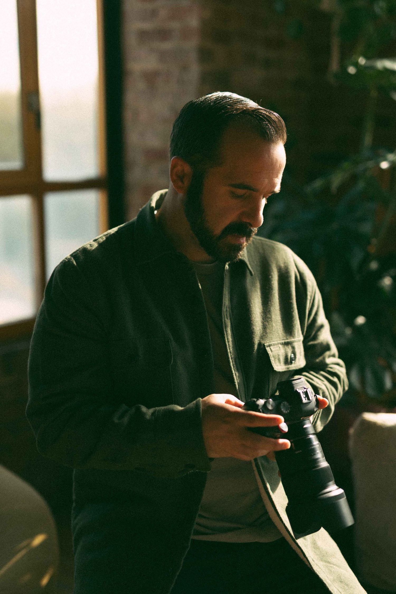 Photographer reviewing shots on camera in warmly lit indoor studio.