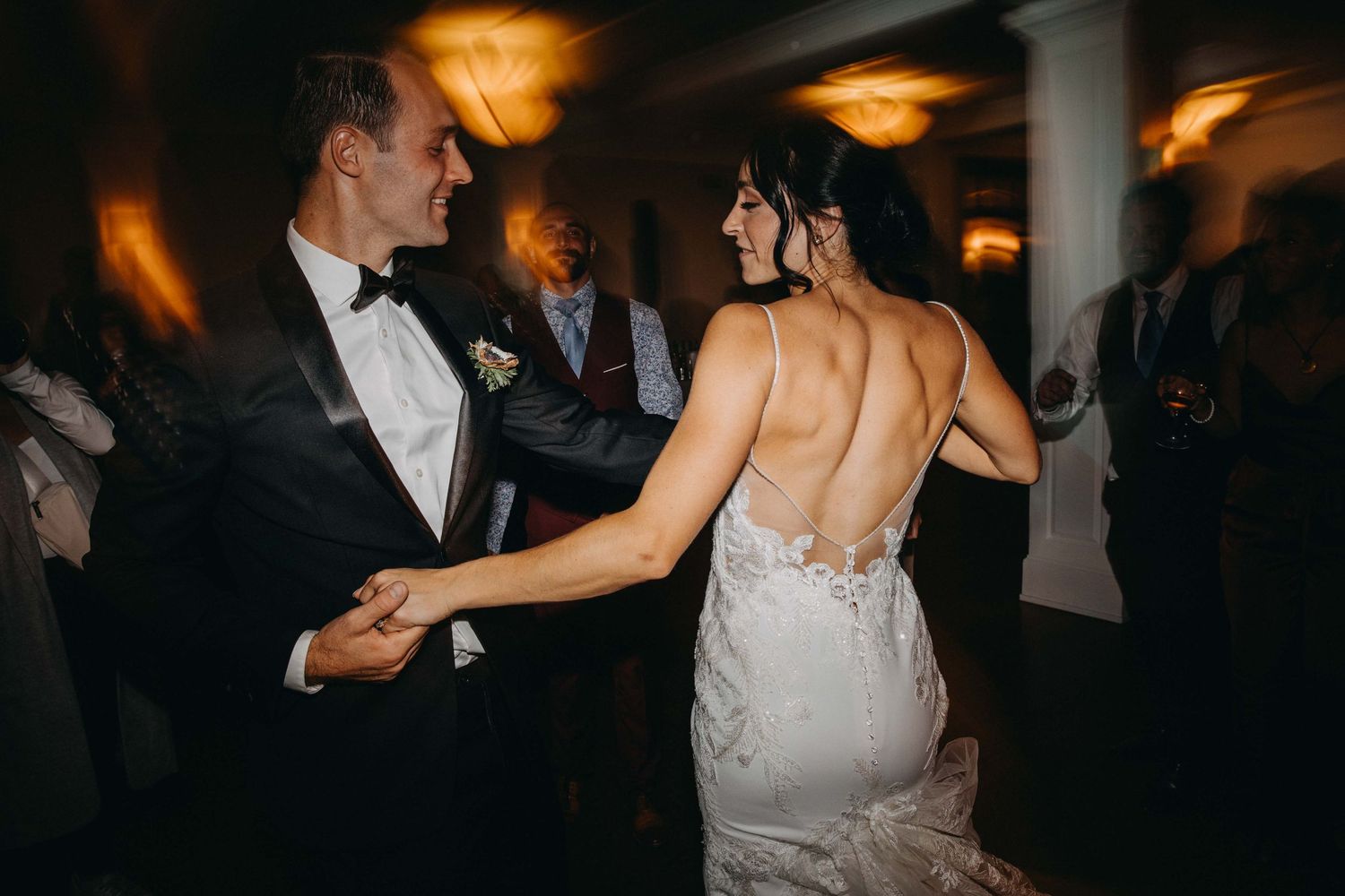 Bride and groom sharing romantic first dance in warmly lit wedding reception ballroom.