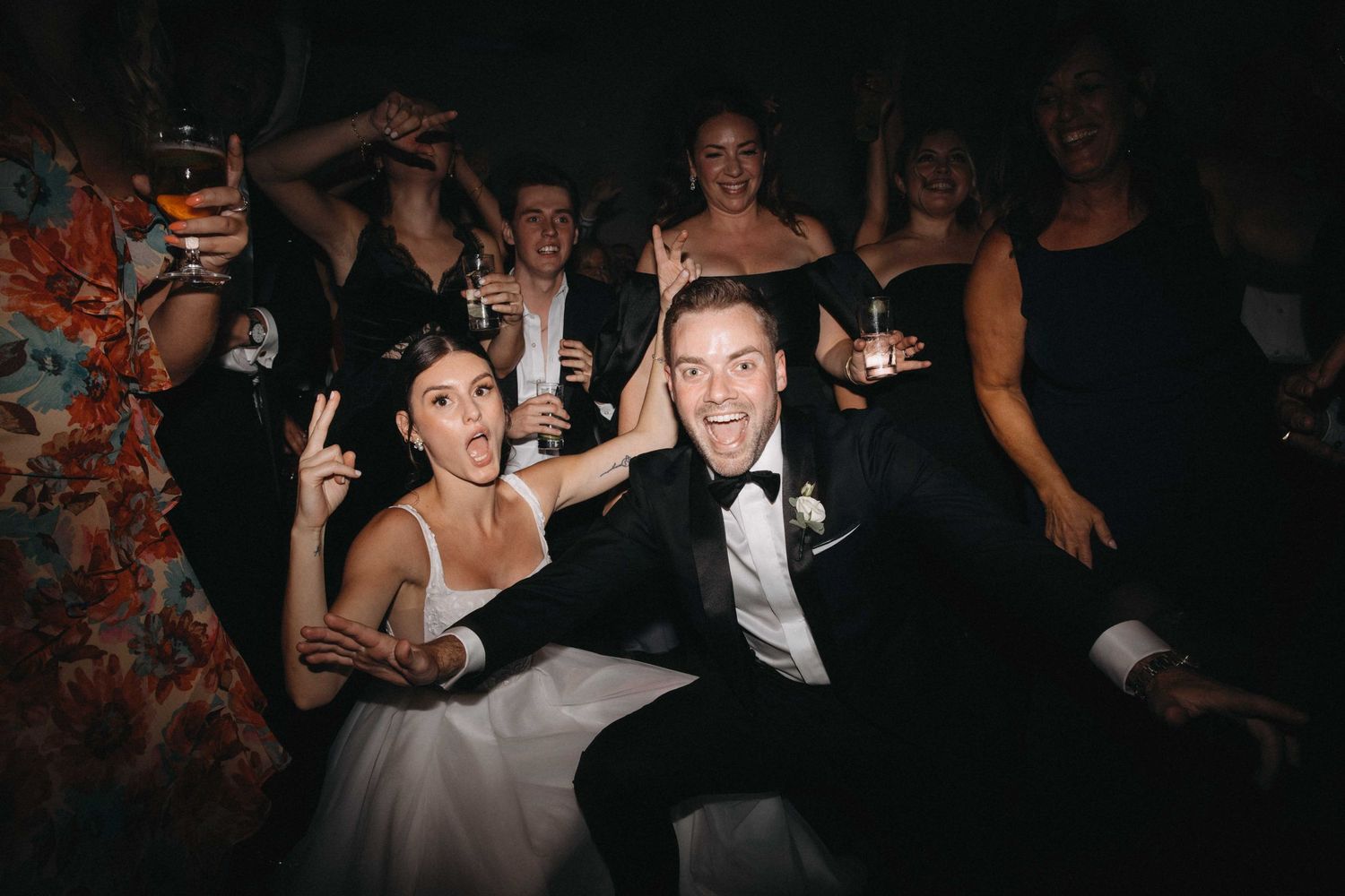 Bride and groom celebrate joyfully with wedding guests at a lively reception party.