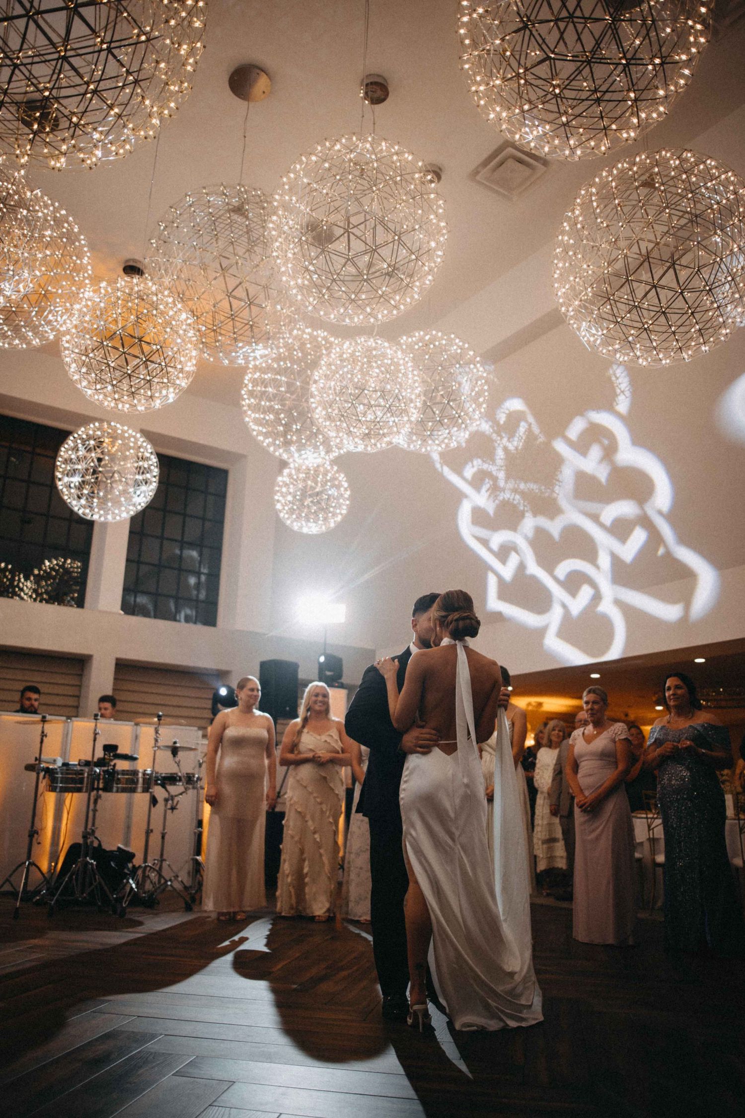 Bride and groom share their first dance under glowing geometric light spheres at wedding reception.