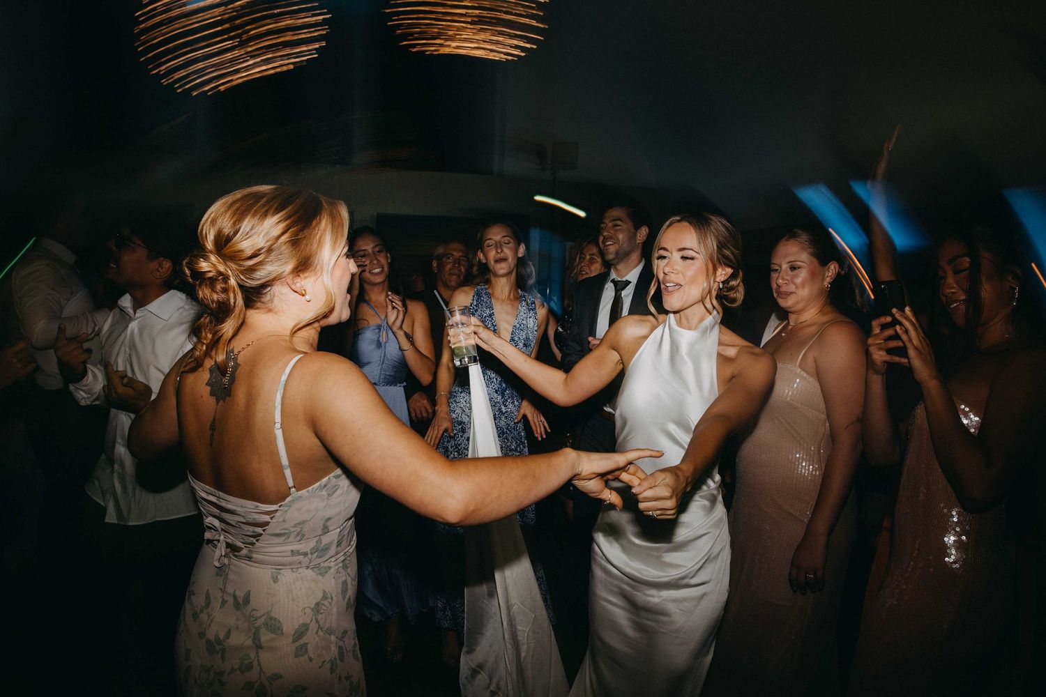Bride and bridesmaids dancing joyfully together at wedding reception celebration.