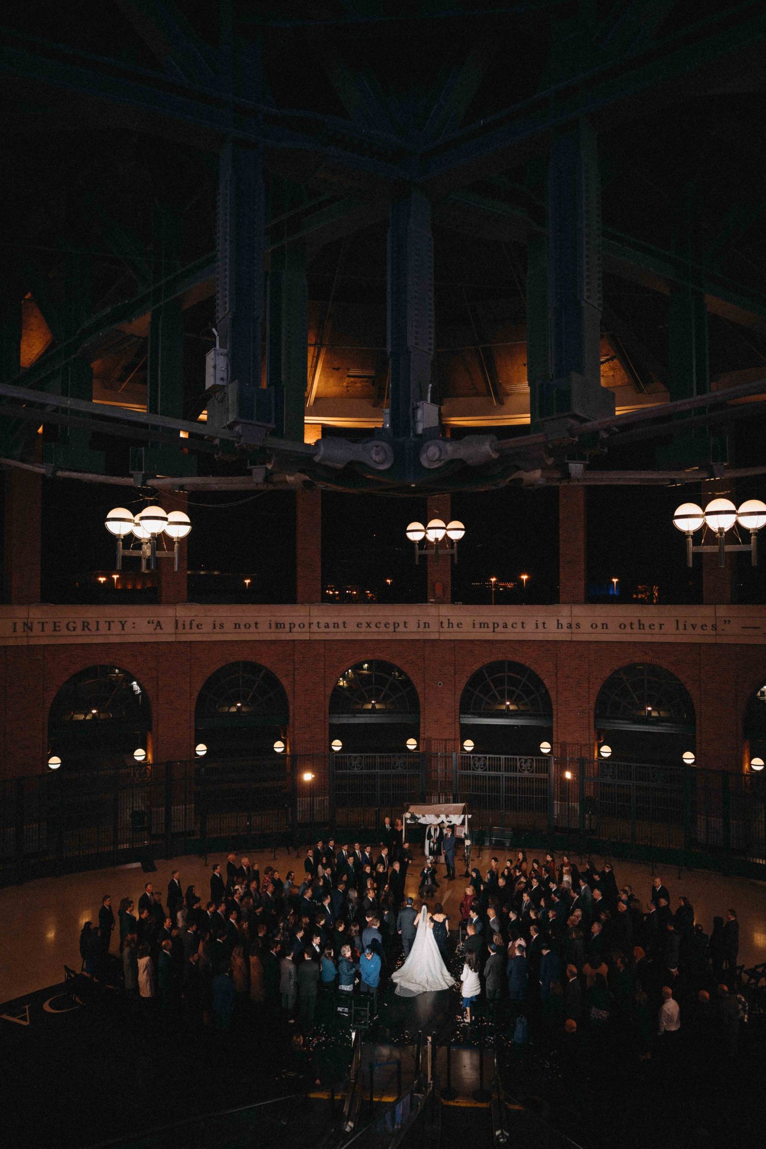 Aerial view of wedding ceremony inside historic domed building with arched windows.
