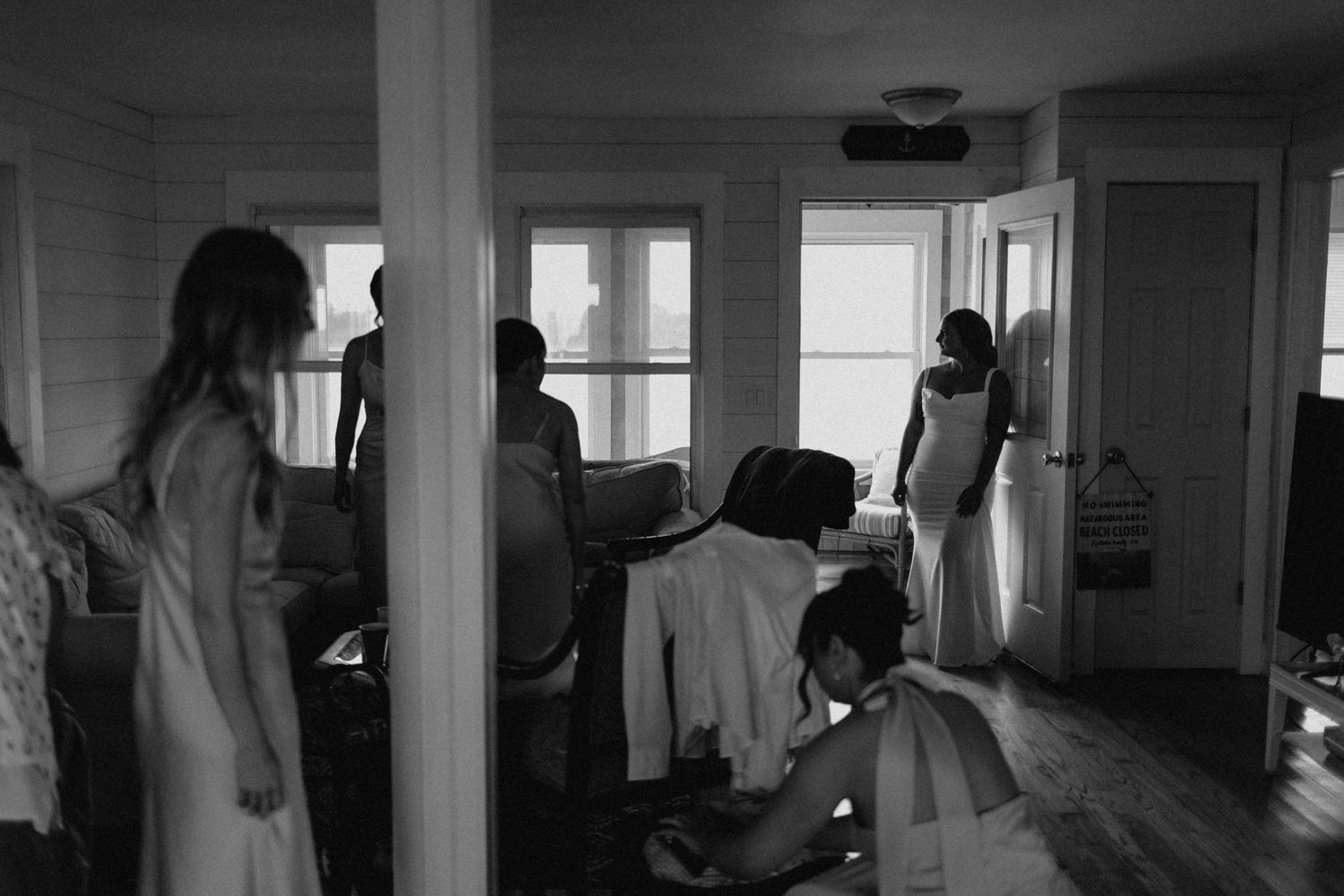 Black and white photo of bridal party getting ready in a cozy cottage room before the wedding.
