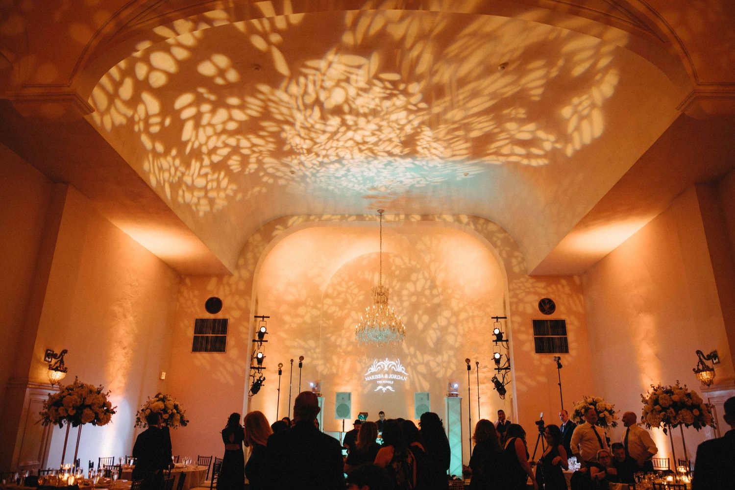Elegant wedding reception venue with arched ceilings adorned with glowing floral light projections.