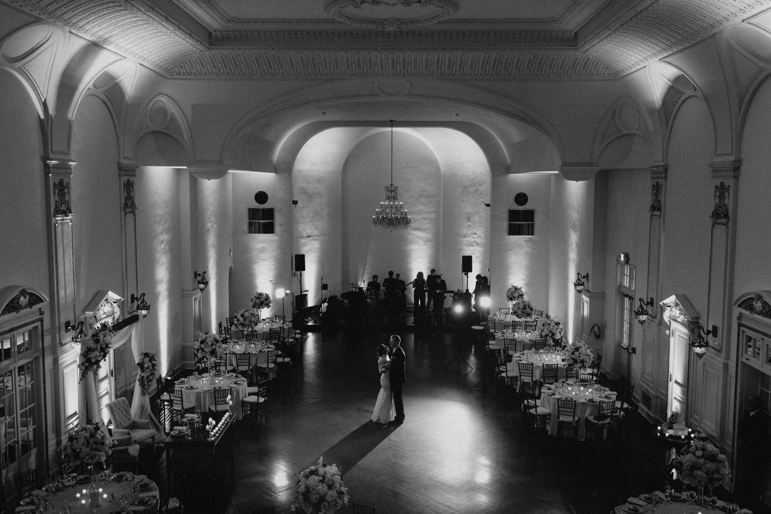 Elegant black and white wedding reception in a grand ballroom with arched ceilings and couples first dance.
