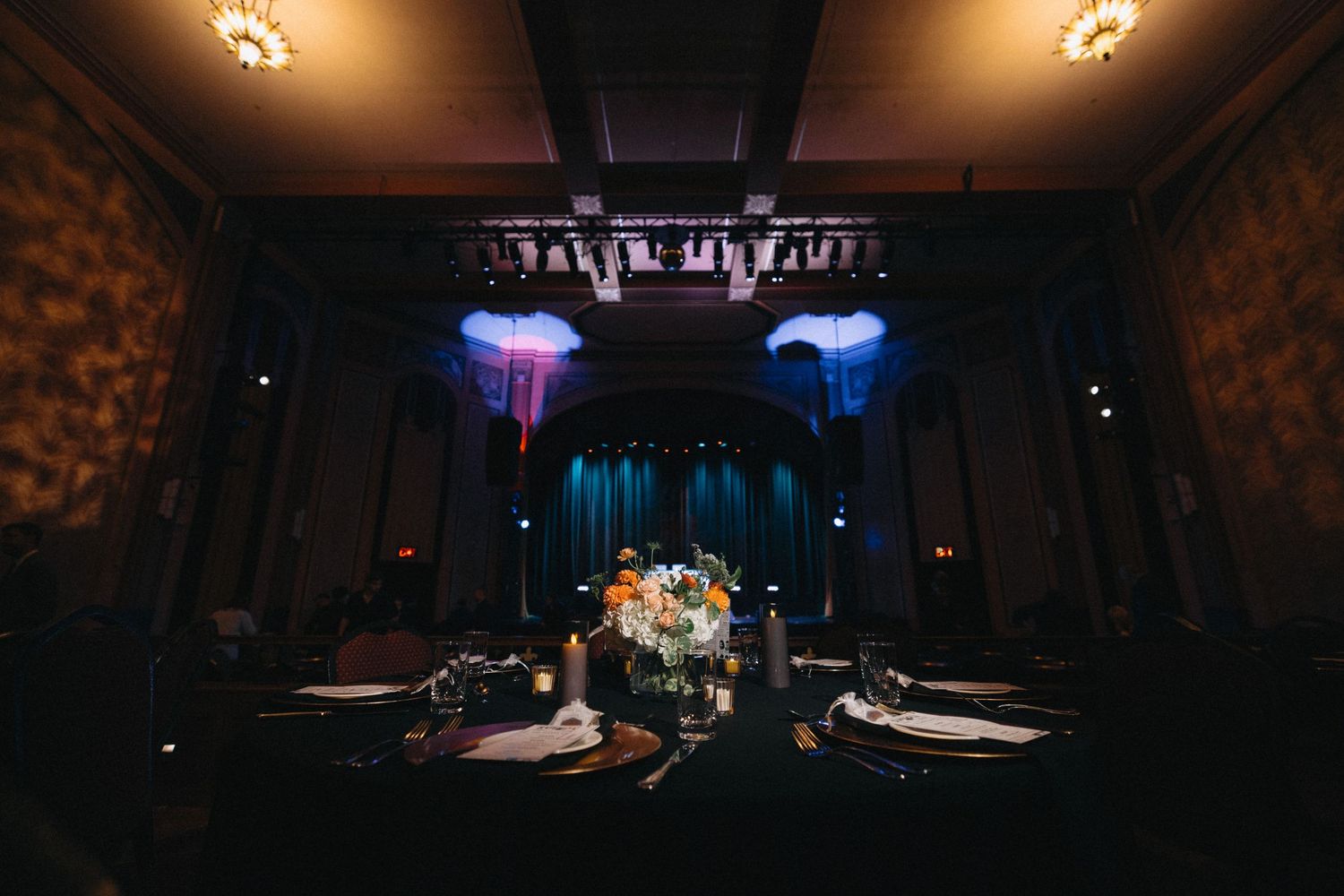 Elegant wedding reception table set under dramatic blue and purple lighting in a historic venue.