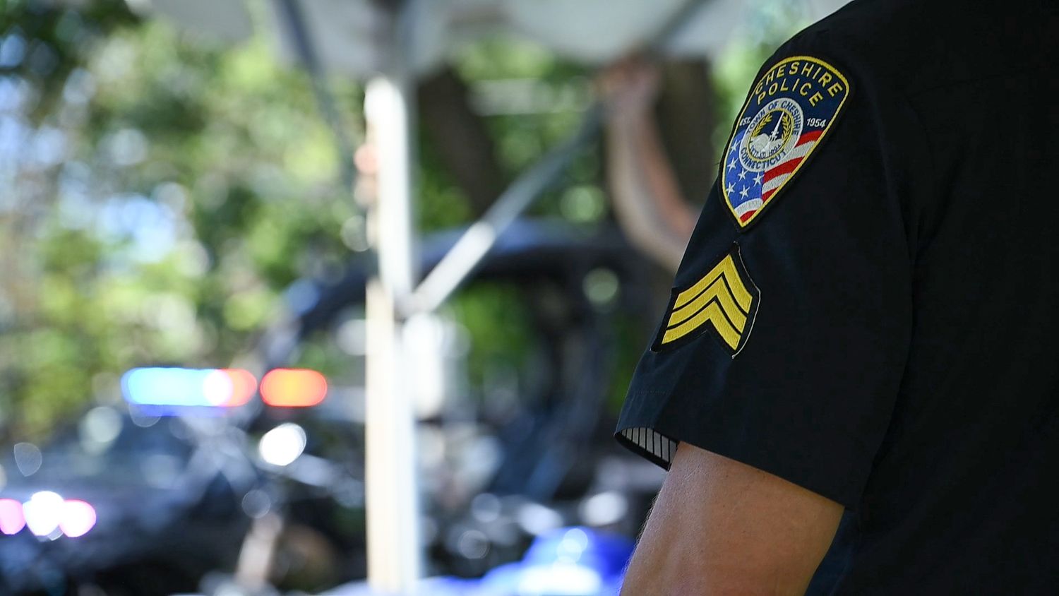 Close-up of a police sergeant badge and patch on a black uniform shirt outdoors.