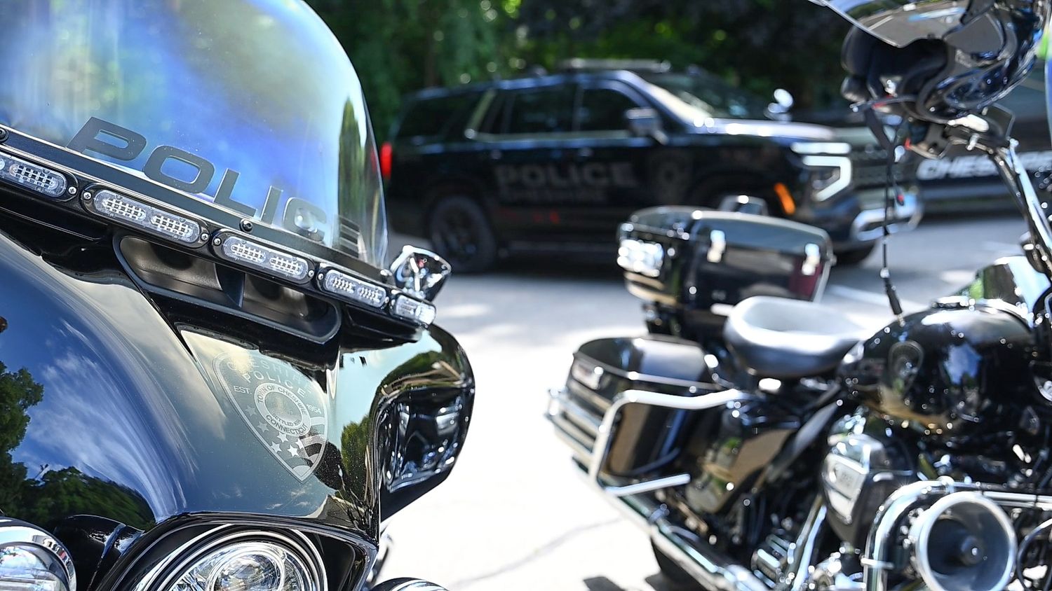 Police motorcycles and patrol SUV parked outdoors on a sunny day, showcasing law enforcement vehicles up close.