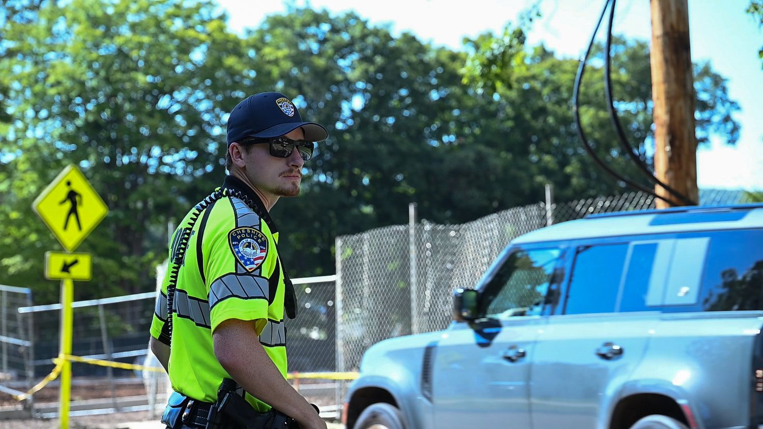 Police officer in high-visibility vest directing traffic near a construction zone on a sunny day.
