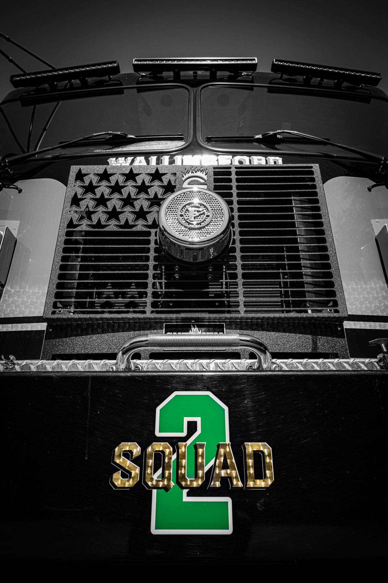 Black and white close-up of Wallingford Squad 2 fire truck front grille with green and gold lettering.