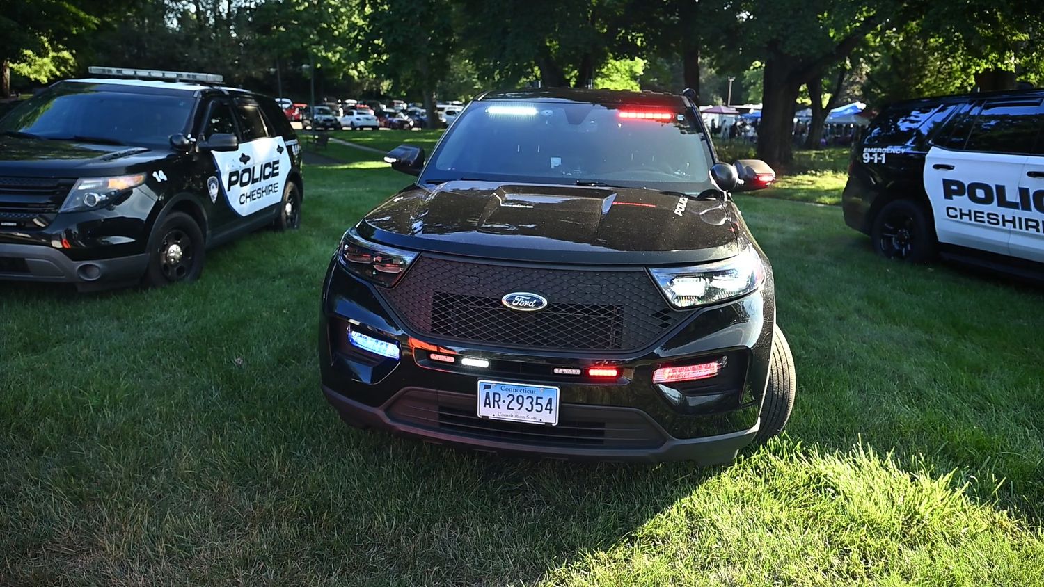 Black Ford Police Interceptor SUV parked on grass at a Cheshire police vehicle display event.