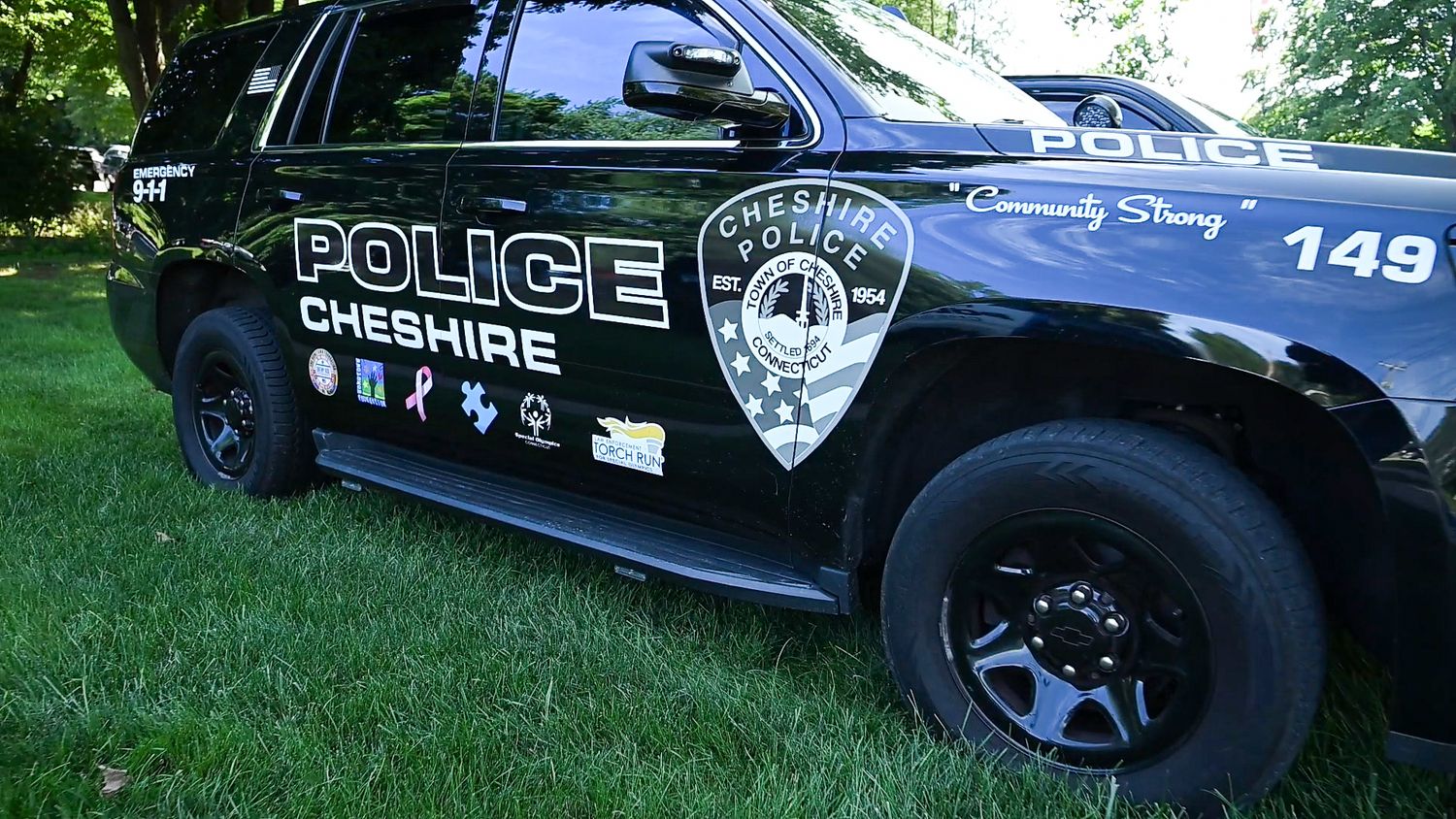 Cheshire Police Department patrol car unit 149 parked on grass, featuring official logo and Community Strong motto.